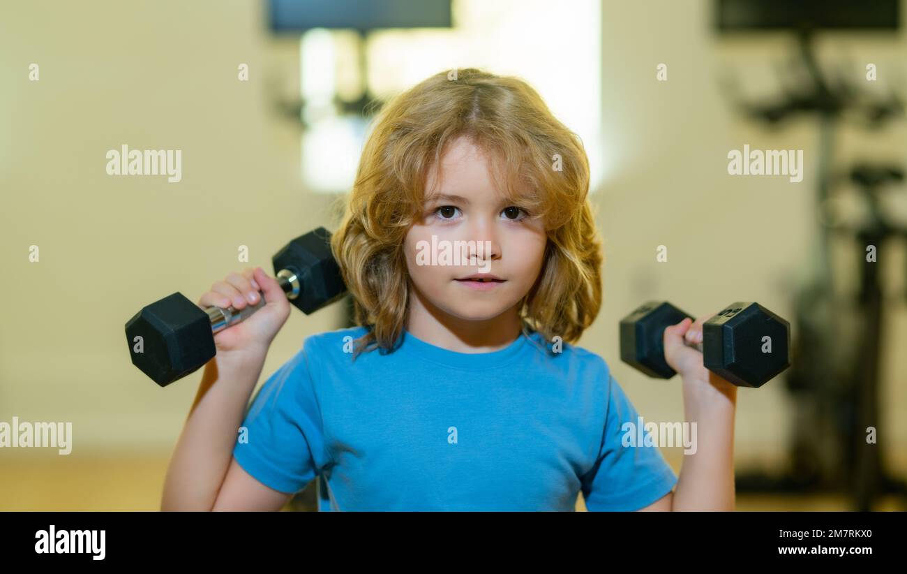 Capretto che alza un dumbbell. Allenamento per bambini carino con manubri. Fitness per bambini. Bambino in palestra. Ragazzo che si allenava con i manubri. Bambini sani. Foto Stock