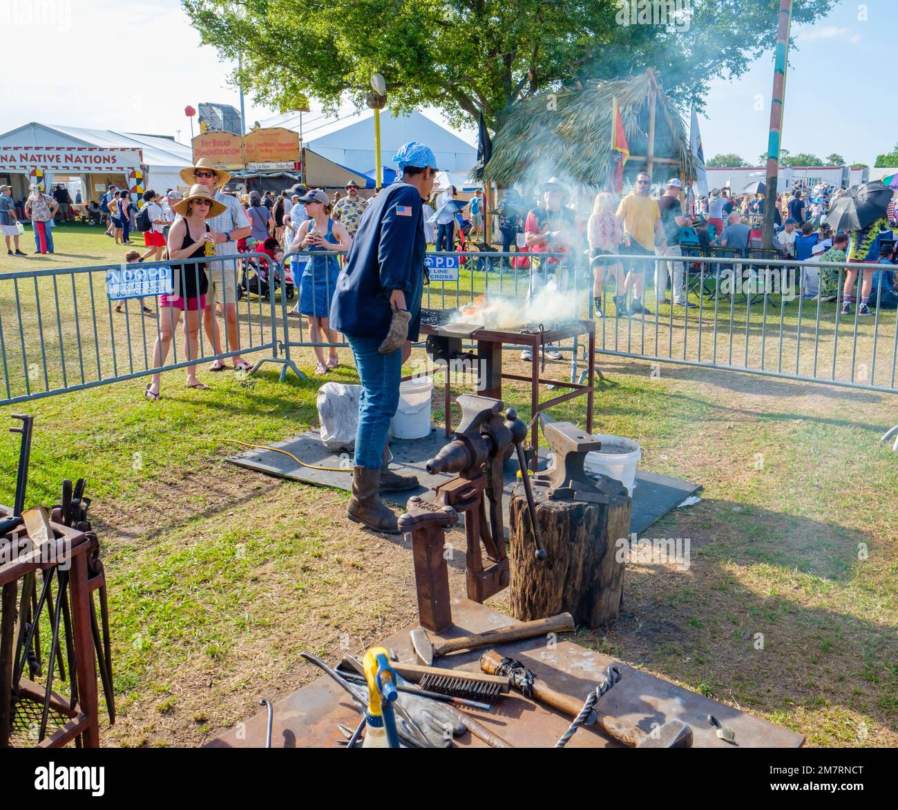 NEW ORLEANS, LA, USA - 1 MAGGIO 2022: L'assistente del fabbro stoca il fuoco al Blacksmith Demo Annex al New Orleans Jazz and Heritage Festival Foto Stock