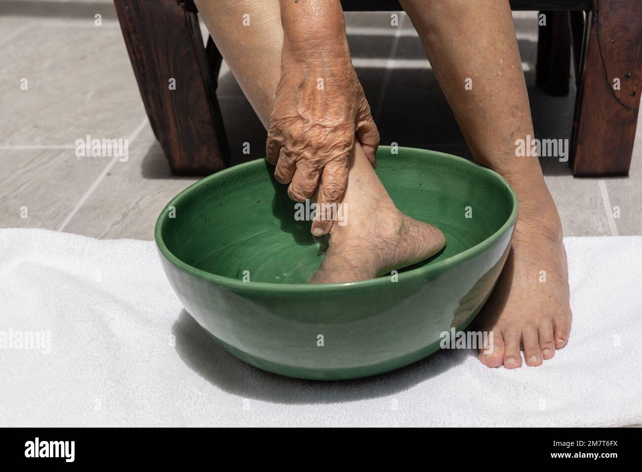 Donna anziana che si immergi i piedi con acqua salata calda a casa. Foto Stock