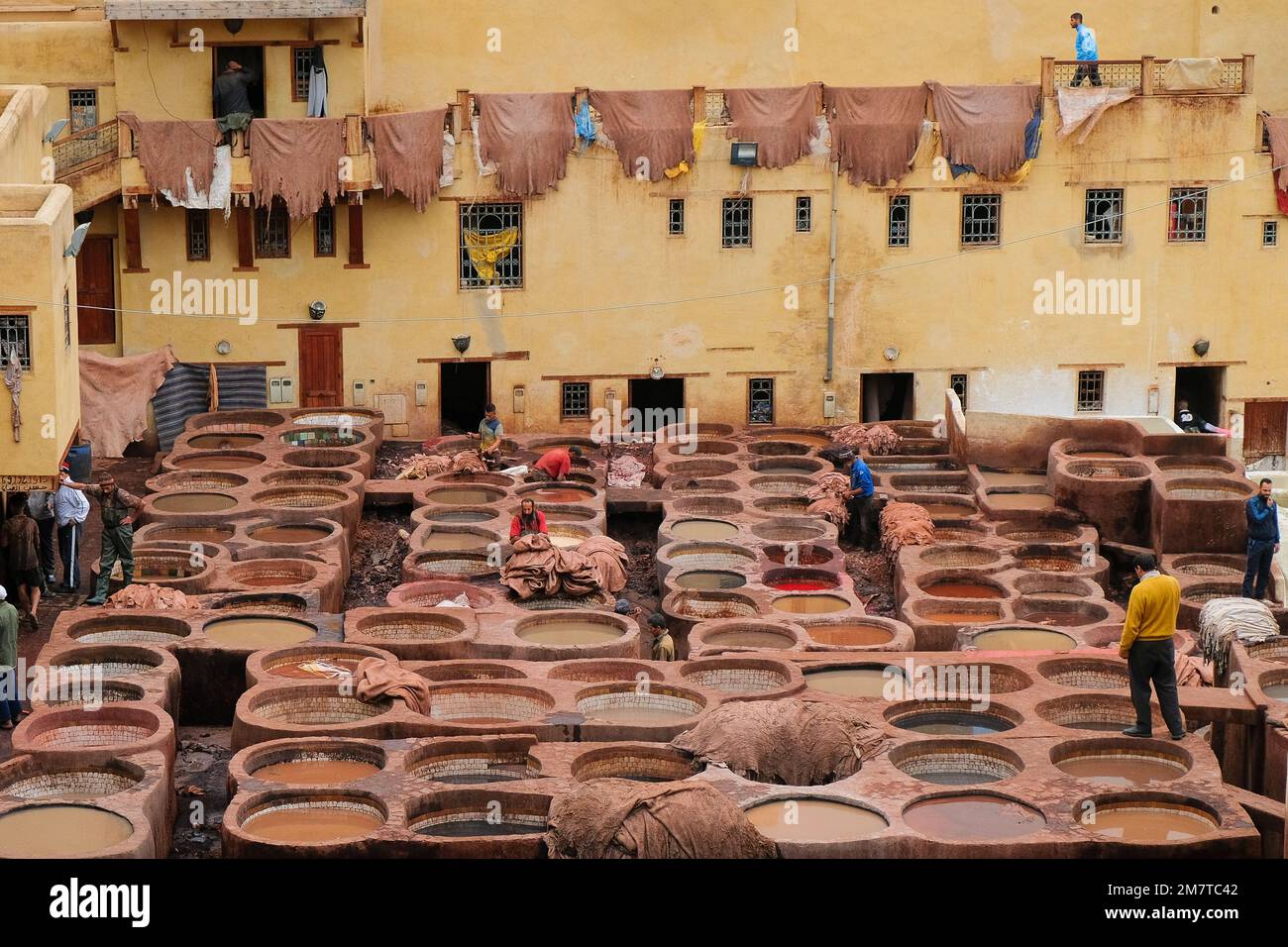 Fez, Marocco - i lavoratori bagnano le pelli di animali su vasi di pietra con tinture a Chouara Tannery a Fes el Bali. industria del 11th ° secolo. Sfondo orizzontale. Foto Stock