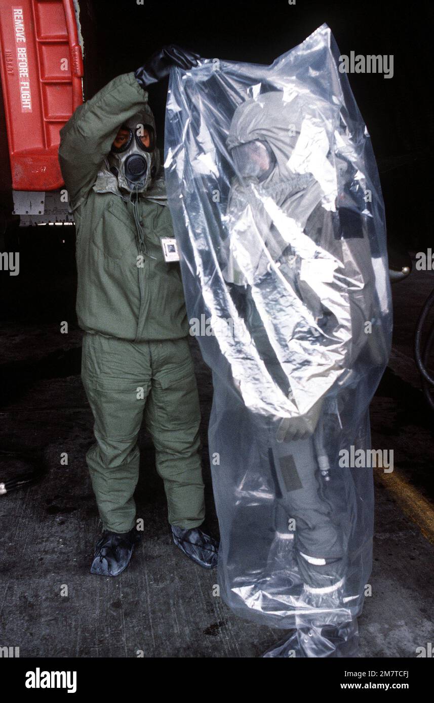 Wogoman aiuta il pilota MAJ Willie Register a indossare la sua custodia protettiva in plastica dopo la sua missione a bordo di un F-4 Phantom II. Wogoman e Register indossano entrambi gli attrezzi da guerra chimici per l'allenamento. Base: Osan Air base Nazione: Repubblica di Corea (KOR) Foto Stock