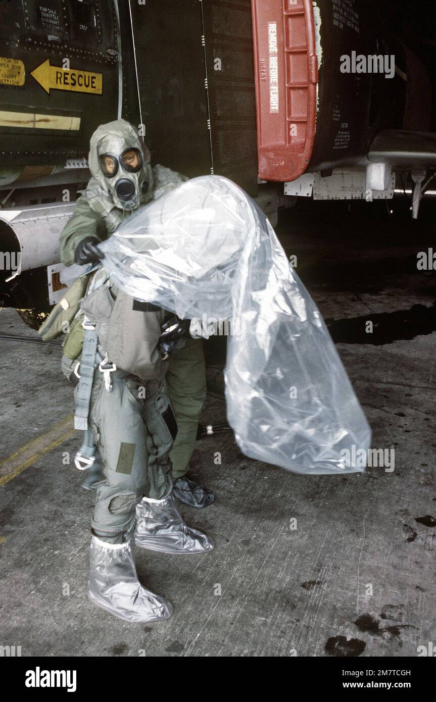 Wogoman aiuta il pilota MAJ Willie Register a togliere la sua borsa protettiva prima della sua missione a bordo di un F-4 Phantom II. Wogoman e Register indossano entrambi gli attrezzi da guerra chimici per l'allenamento. Base: Osan Air base Nazione: Repubblica di Corea (KOR) Foto Stock