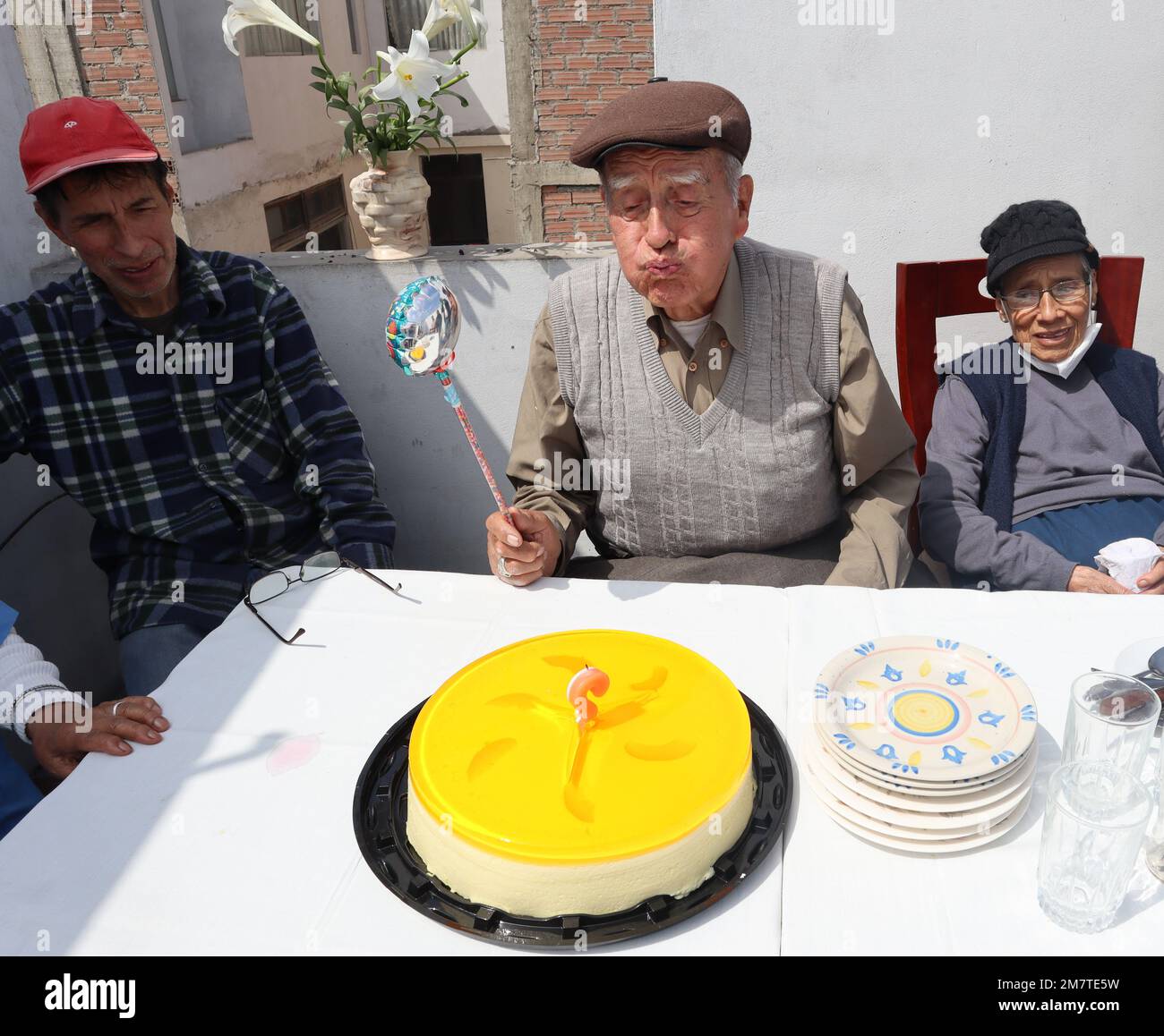 Anziano festeggia il suo compleanno a casa di famiglia. Soffiare fuori candela e tenere un pallone. Foto Stock