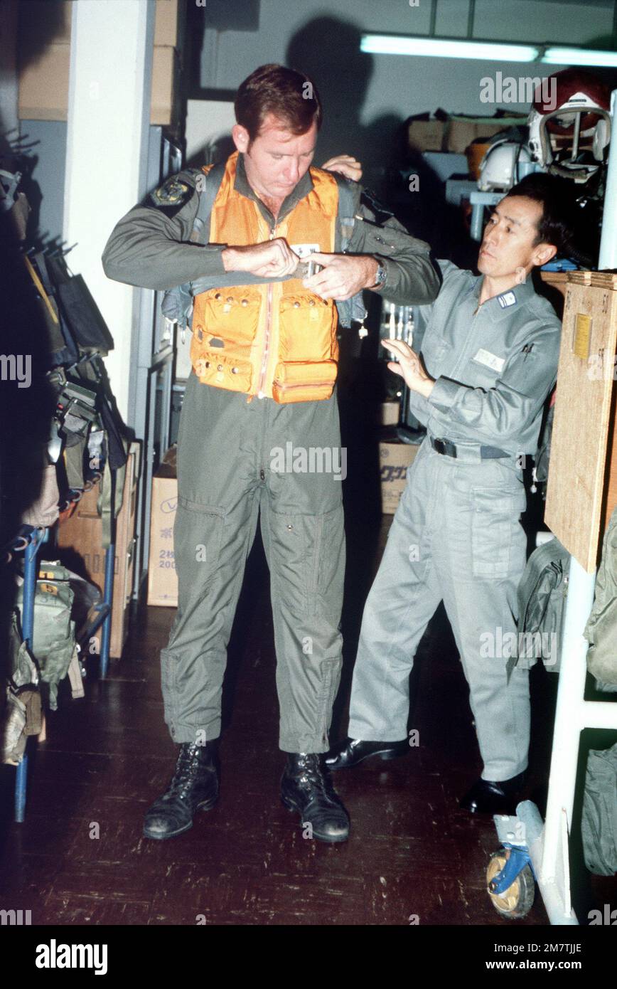 LT. Steve Schmidt si addice prima del suo volo con l'aiuto di Akio Morikagi. Entrambi gli uomini stanno partecipando agli esercizi COPE North '82-1A che si svolgono presso le basi aeree di Kadena e Naha. Soggetto operativo/Serie: COPE NORTH '82-1A base: Kadena Air base Stato: Okinawa Paese: Giappone (JPN) Foto Stock