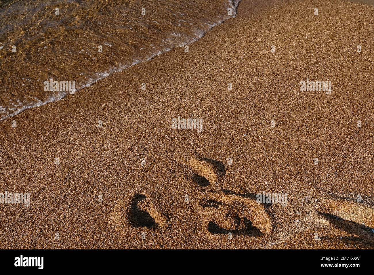 Primo piano di impronte lavate sulla bellissima spiaggia di Mylopotas in Grecia iOS Foto Stock