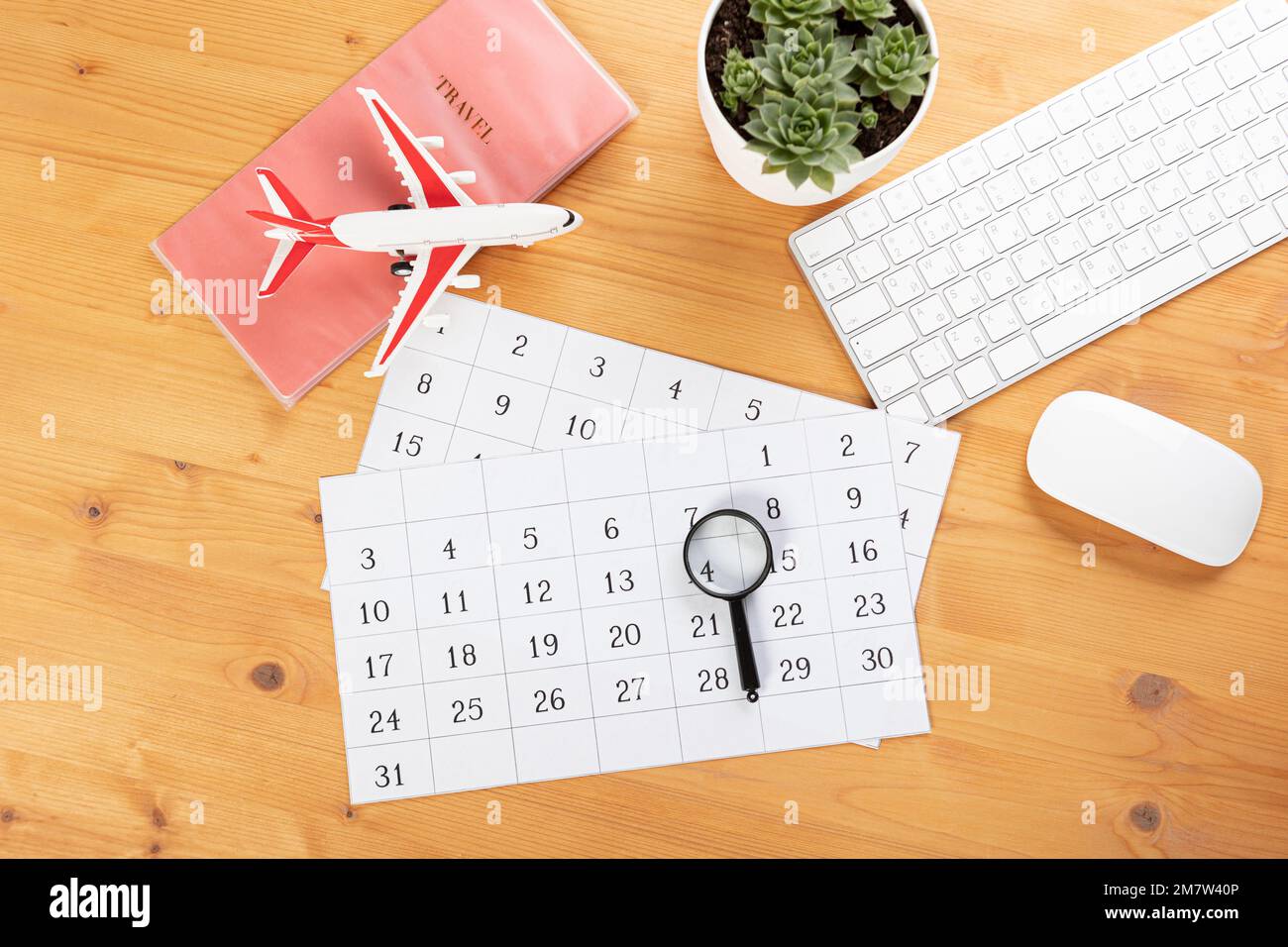 Calendario e promemoria per viaggi di lavoro, viaggi e vacanze. aliante sul desktop con aeroplano e lente d'ingrandimento e penna, tastiera. marcatura importante Foto Stock