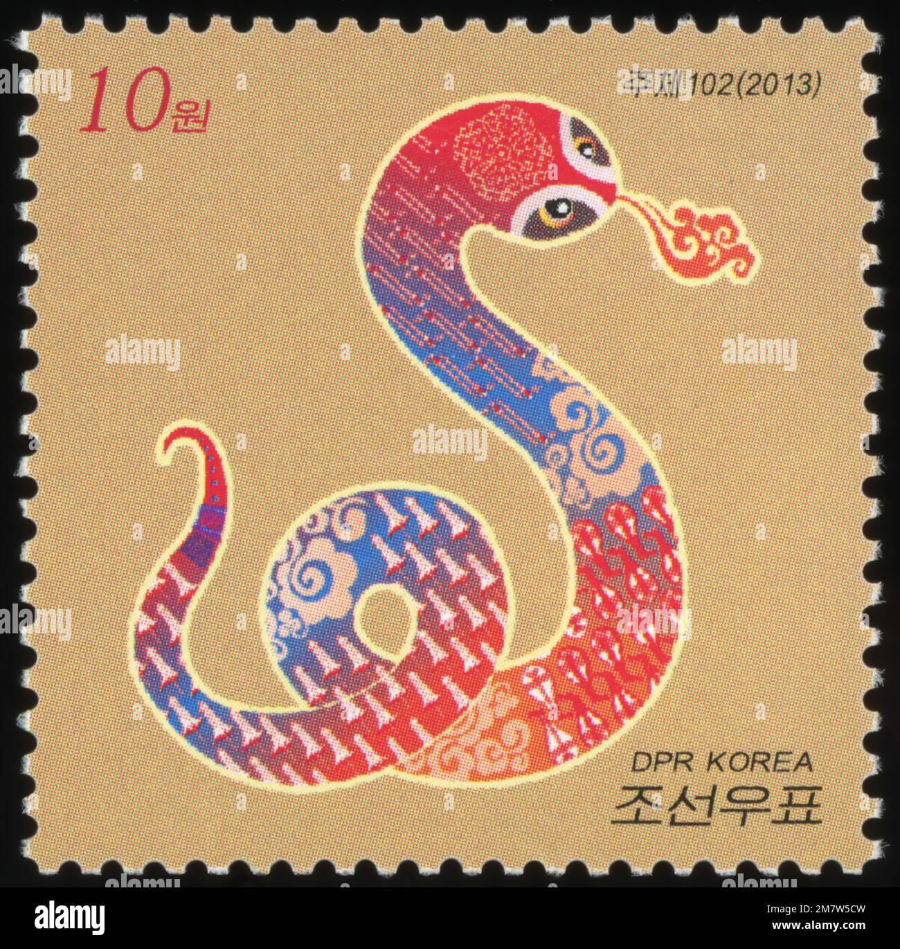 Francobollo nordcoreano del 2013 che celebra l'anno del serpente, con una colorata illustrazione di serpente stilizzata su sfondo dorato. Foto Stock