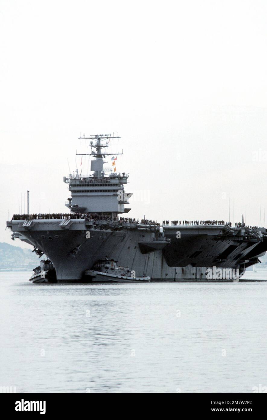 Gli equipaggi allineano le rotaie a bordo della portaerei a energia nucleare USS ENTERPRISE (CVN-65) mentre è assistita in posizione di attracco dal grande rimorchiatore portuale USS POUGHKEEPSIE (YTB-813). L'IMPRESA sta ritornando da una breve crociera a seguito del recente rinnovo che ha incluso la ricostruzione della sovrastruttura. Base: Naval Air Station, Alameda Stato: California (CA) Paese: Stati Uniti d'America (USA) Foto Stock