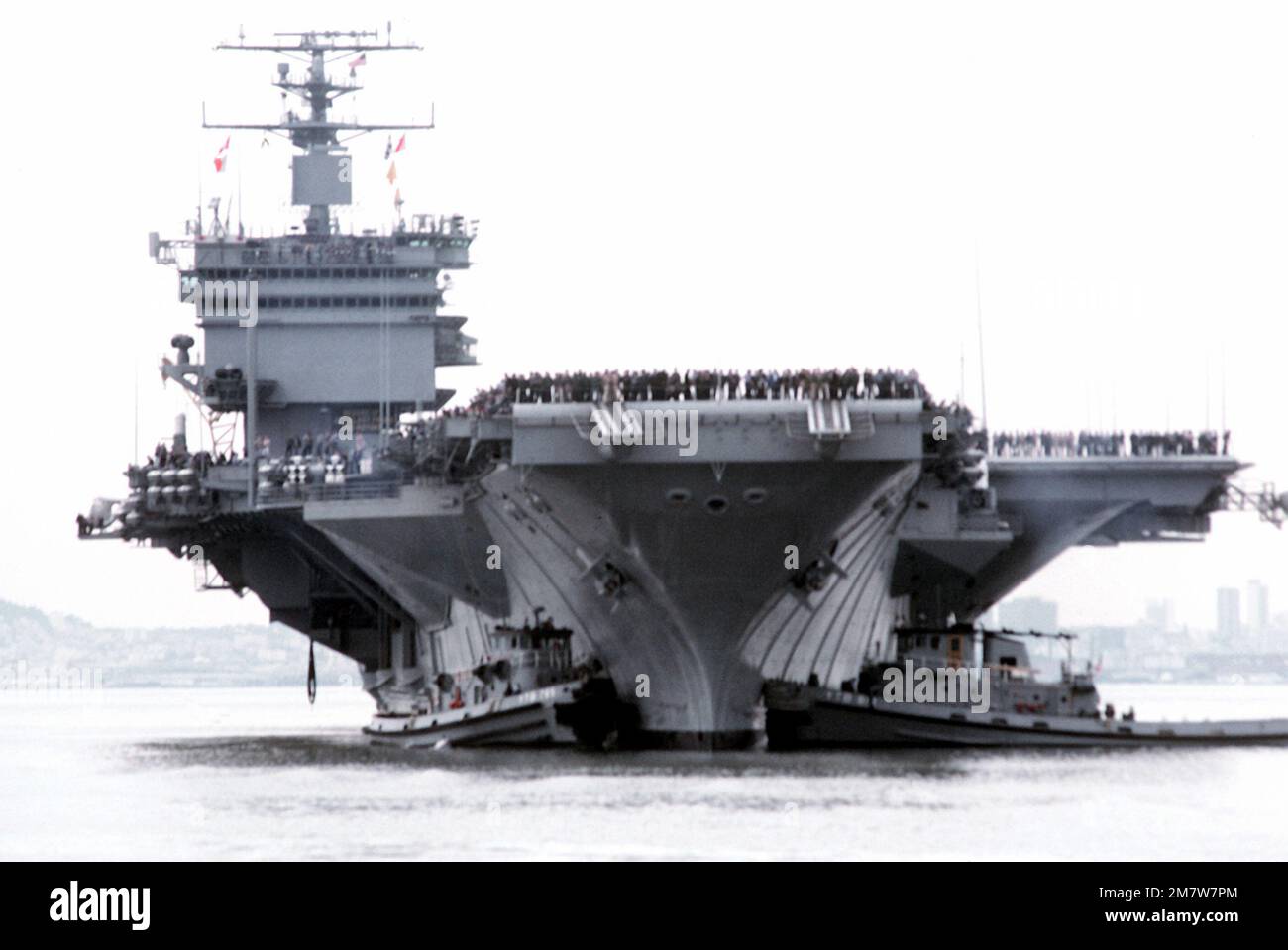 Una prua in vista della portaerei nucleare USS ENTERPRISE (CVN-65) assistita in posizione di attracco da due grandi rimorchiatori portuali. Gli equipanti si addetta alla ferrovia mentre L'IMPRESA completa una breve crociera a seguito del recente restauro che ha incluso la ricostruzione della sovrastruttura. Base: Naval Air Station, Alameda Stato: California (CA) Paese: Stati Uniti d'America (USA) Foto Stock