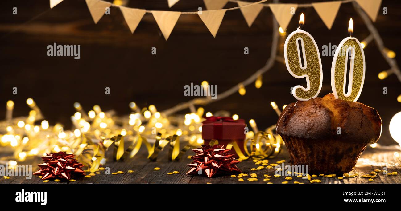 Numero 90 candele brucianti festive dorate in una torta, sfondo di festa in legno. Novanta anni dalla nascita. il concetto di celebrare un compleanno, un Foto Stock