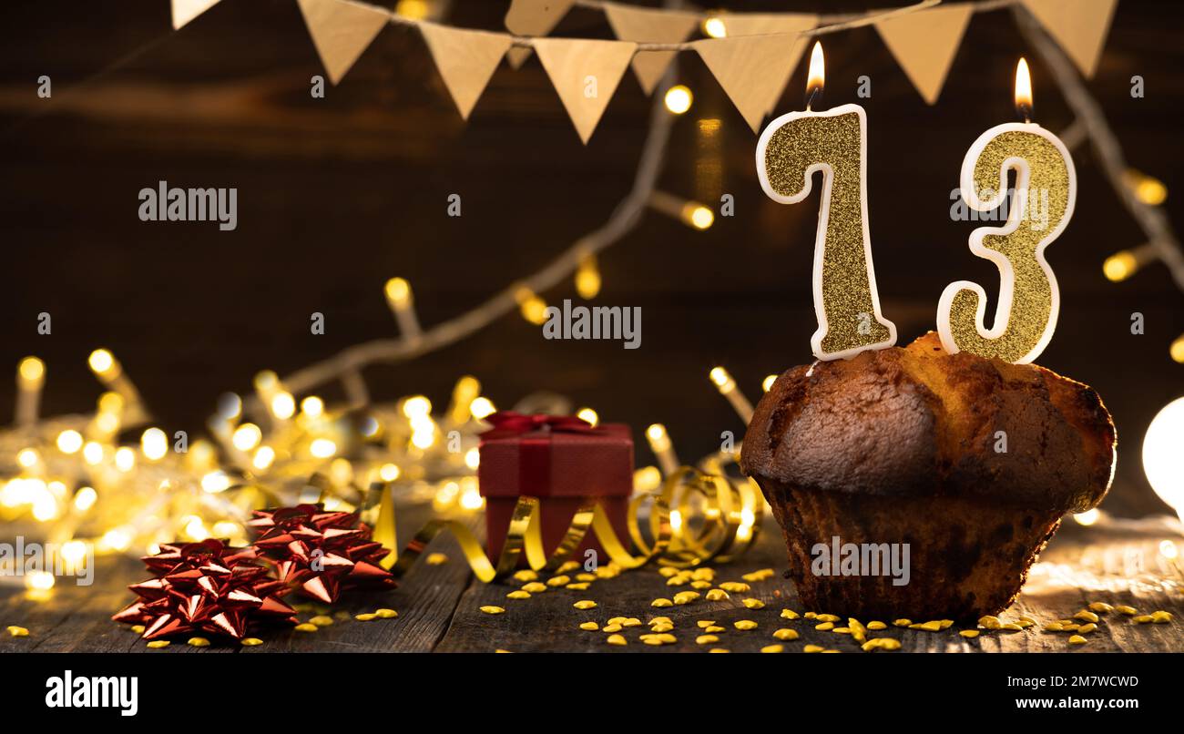 Numero 73 candele brucianti festive dorate in una torta, sfondo di festa in legno. settantatré anni di nascita. il concetto di celebrare un compleanno, un Foto Stock