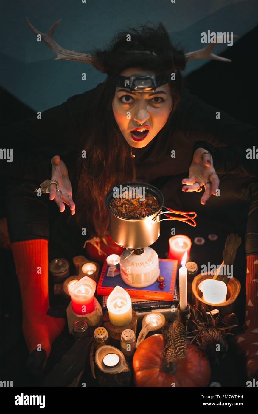 Primo piano donna sciamano con corna grimacing sopra vaso ritratto Foto Stock