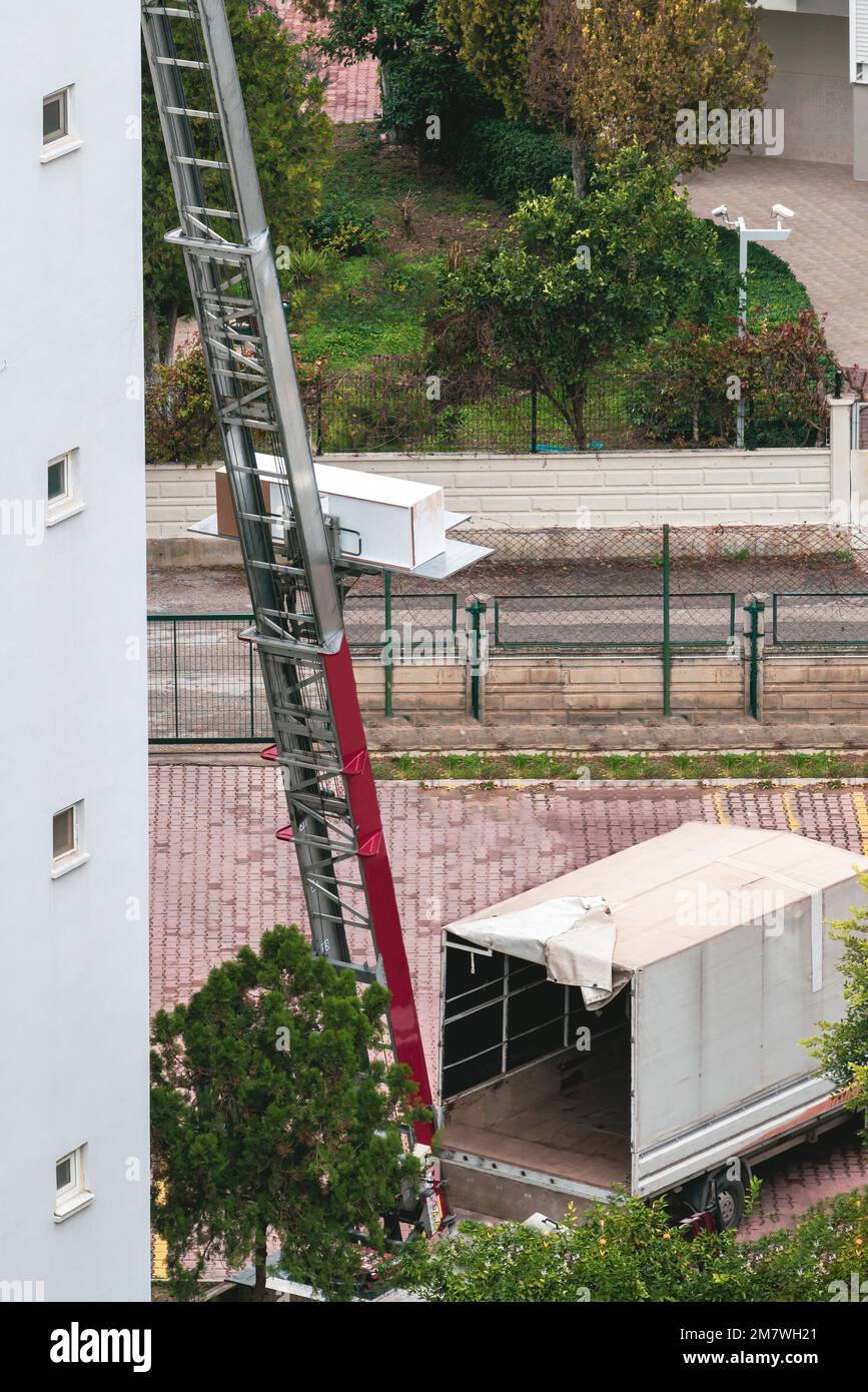 Rimozione iniziale con sollevatore idraulico. Trasportatori che trasportano merci in ascensore dalla finestra dell'edificio Foto Stock