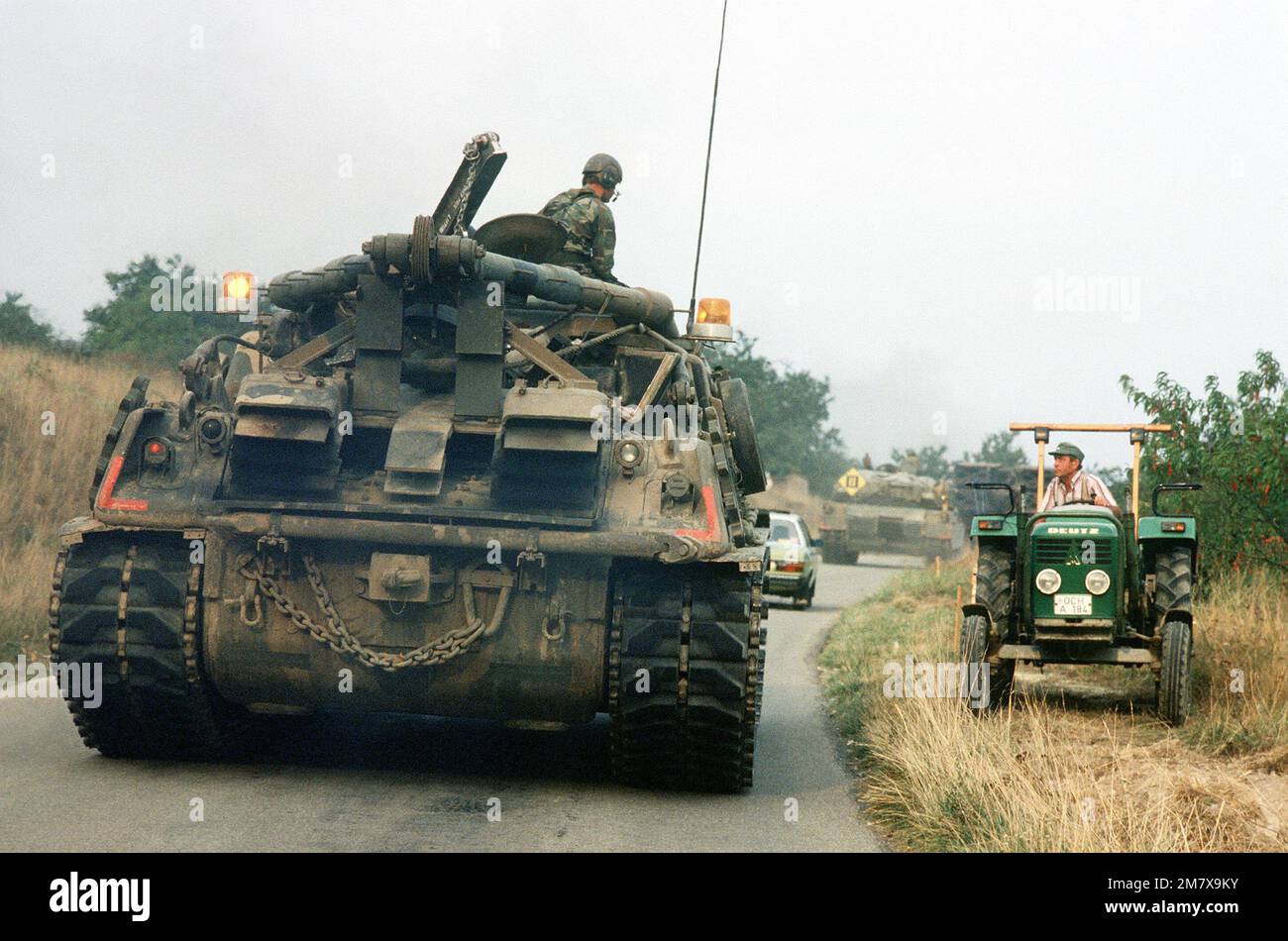 STATI UNITI Army M1 Abrams carri armati si uniscono automobili su una strada attraverso la campagna tedesca, un agricoltore e trattore è fuori strada per fare spazio per i carri armati giganti, durante REFORGER '82, l'esercizio di addestramento militare multi-nazionale. Data esatta dell'acquisizione sconosciuta. Oggetto/Serie: REFORGER '82 Paese: Deutschland / Germany (DEU) Foto Stock