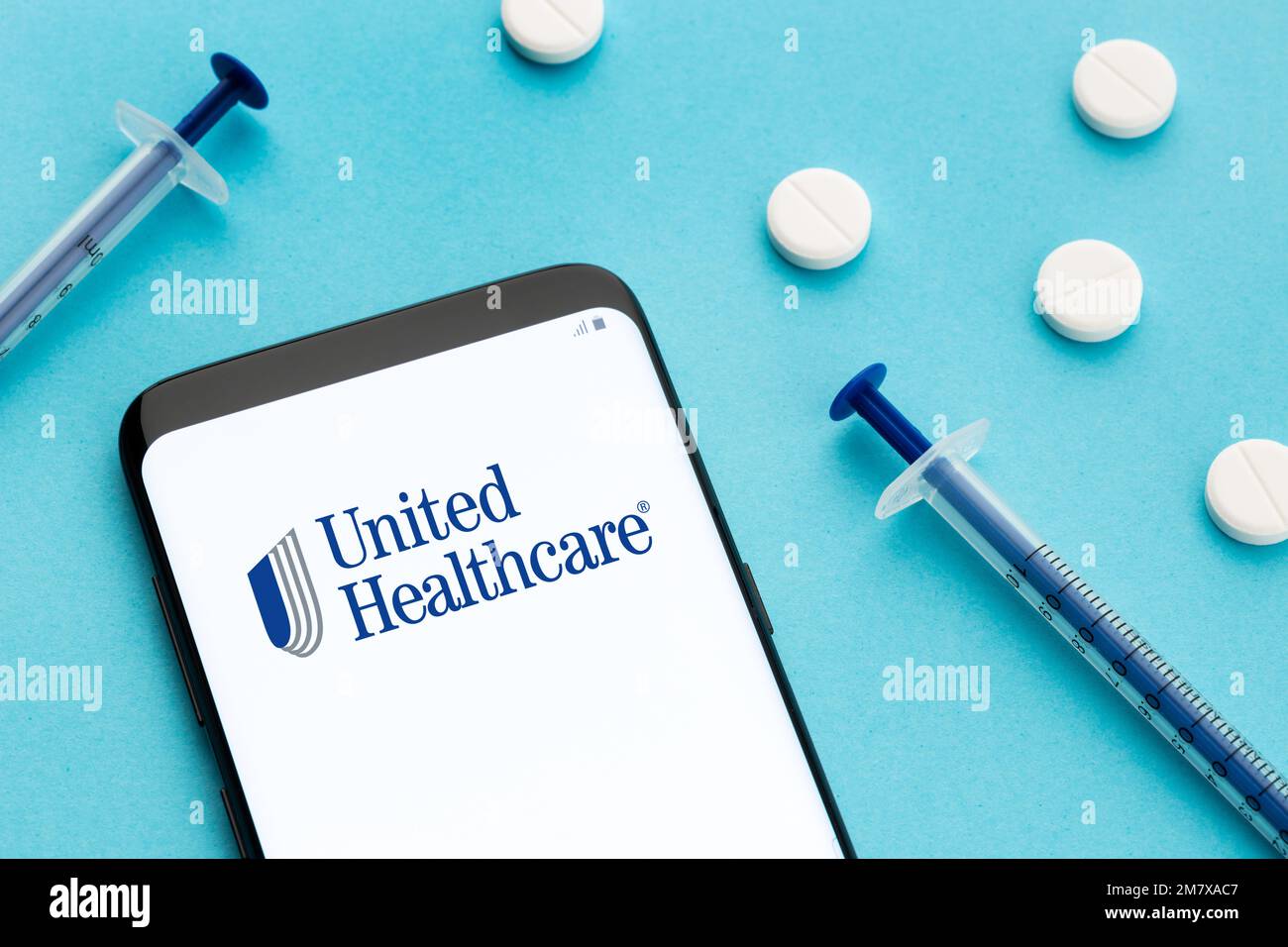 Galicia, Spagna; 8 giugno 2021 : logo Unitedhealthcare su pillole e siringa per smartphone su sfondo blu Foto Stock