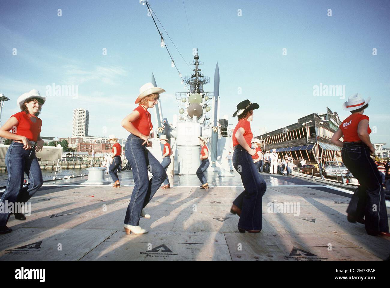 Gli uomini d'equipaggio osservano le ospiti femminili mentre si esibiscono in una danza quadrata sul ponte posteriore dell'incrociatore missilistico guidato USS LEAHY (CG-16) durante la Seattle Sea Fair 1982. Sullo sfondo sono visibili i doppi missili standard-RM SAM (88) su un lanciatore Mark 26 Mod. Base: Seattle Stato: Washington (WA) Paese: Stati Uniti d'America (USA) Foto Stock