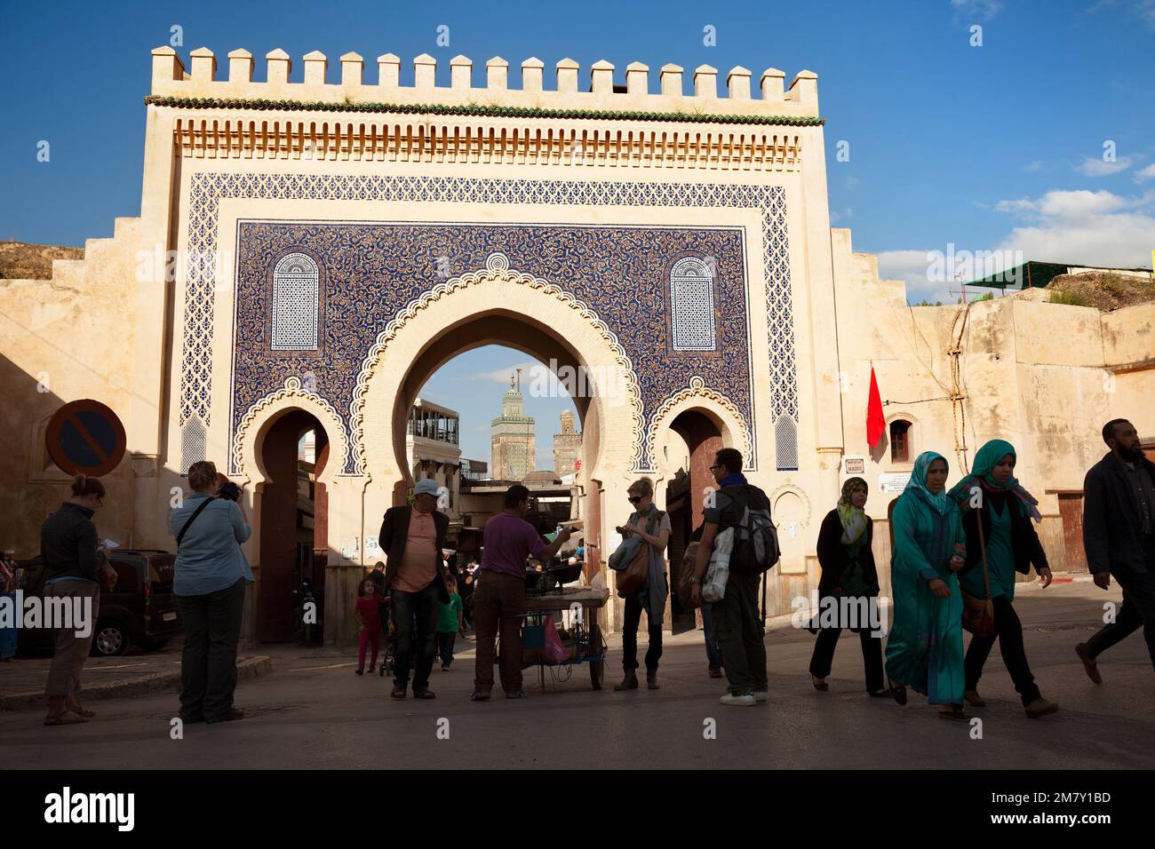 Fez, Marocco-24 marzo 2014: Il Bab Bou Jeloud è una recente aggiunta a Fes El Bali, essendo stato costruito intorno al 1913. Il minareto di Medersa Bou Inania è Foto Stock