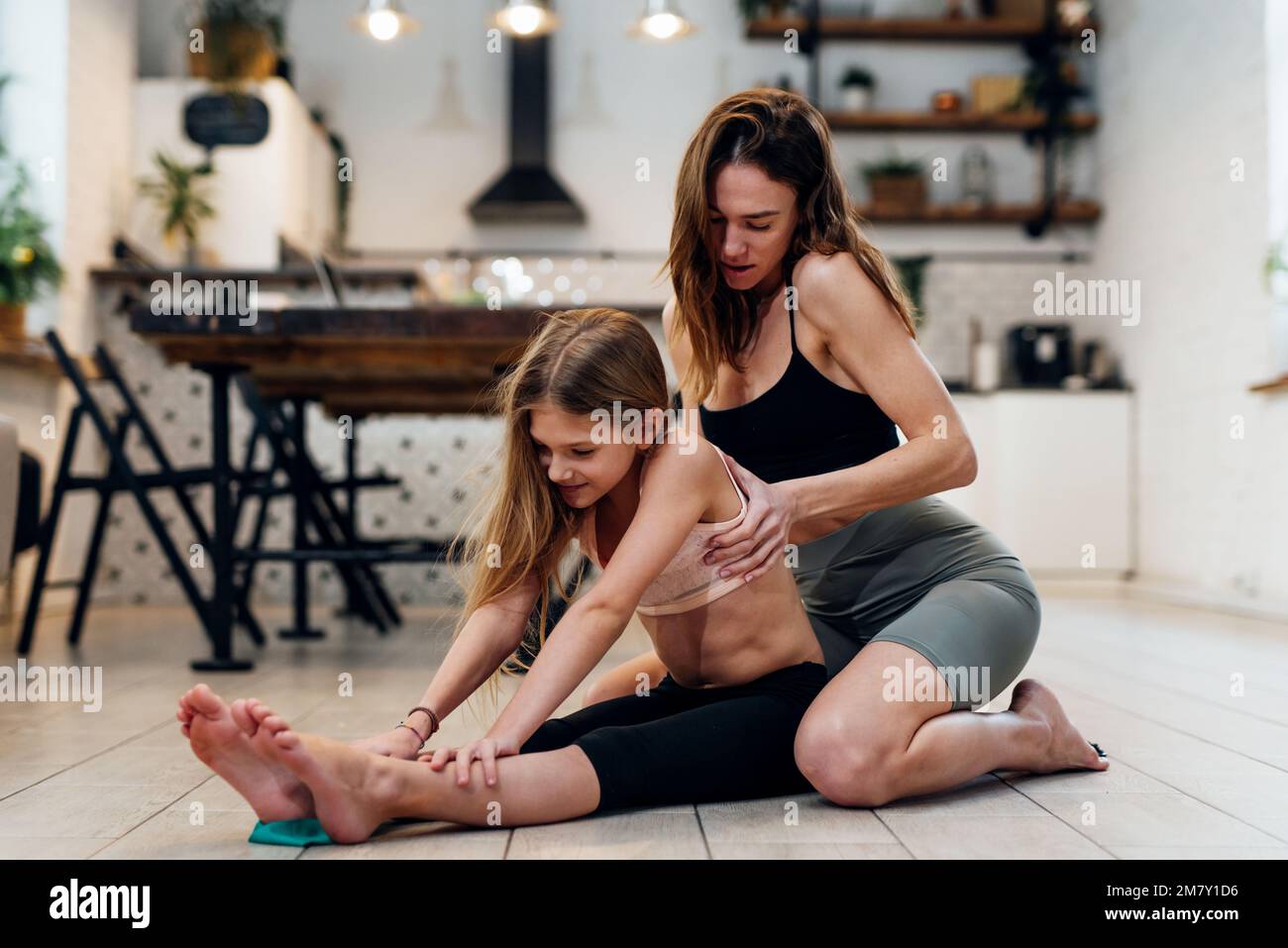 La ragazza e la sua mamma fanno sport a casa stretching. Foto Stock