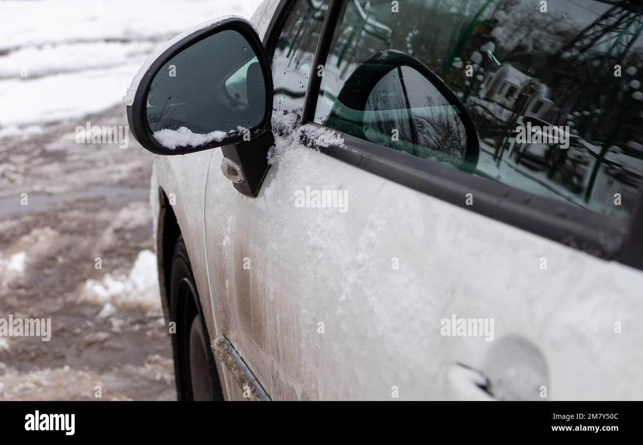 Giovane donna di pulizia vetri auto da neve nella stagione