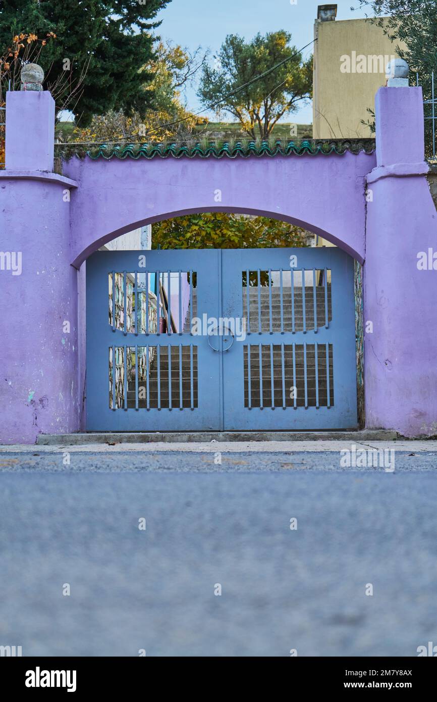 Una porta metallica grigia con parete viola in una strada marocchina Foto Stock