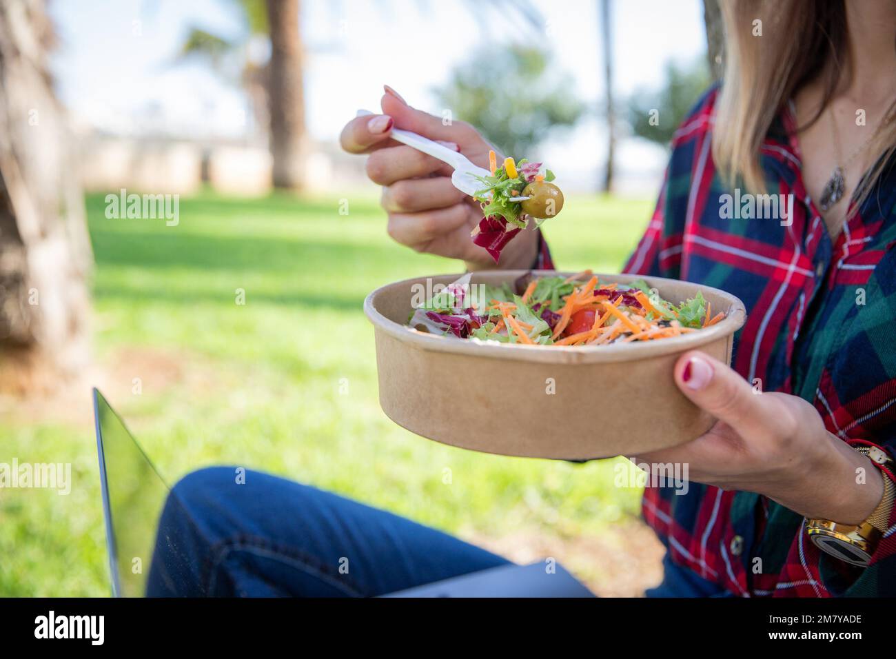 Primo piano di un'insalata mangiata da una ragazza seduta in un parco pubblico, cibo vegano, stile di vita sano Foto Stock