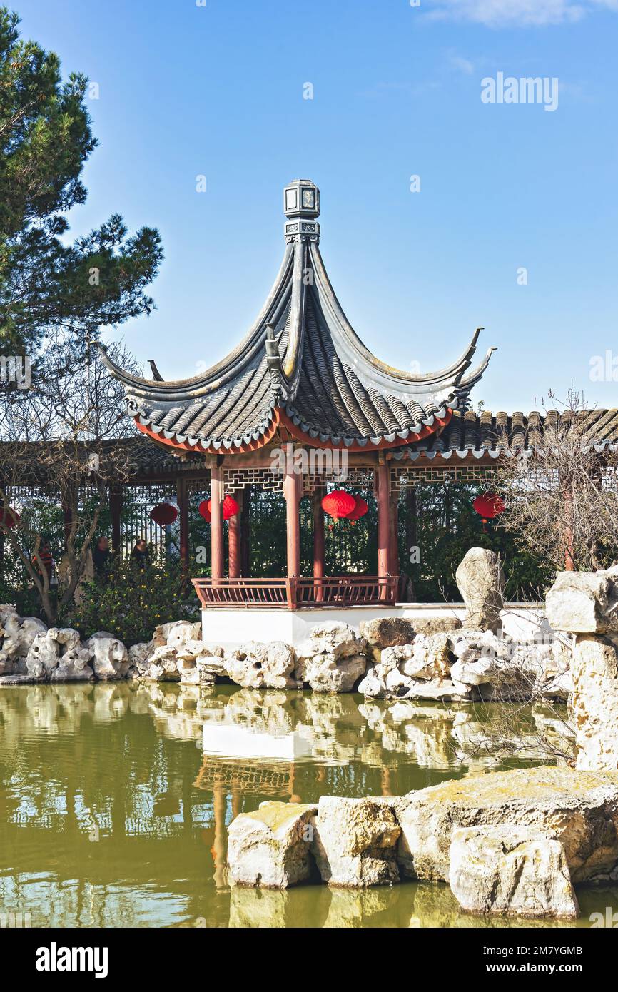 Gazebo cinese in giardino con lanterne tradizionali rosse cinesi sulla riva  del laghetto delle carpe sacrali. Le lanterne rosse tradizionali cinesi  sono appese nel gard Foto stock - Alamy