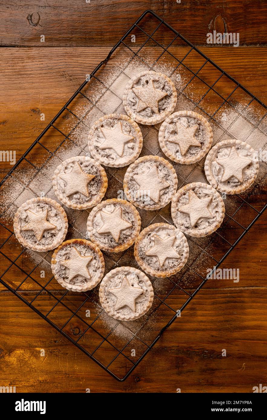 Piatto mettere mince torte sormontate con stelle di pasticceria, spolverato con zucchero a velo su sfondo di legno scuro: Natale casa cottura. Foto Stock