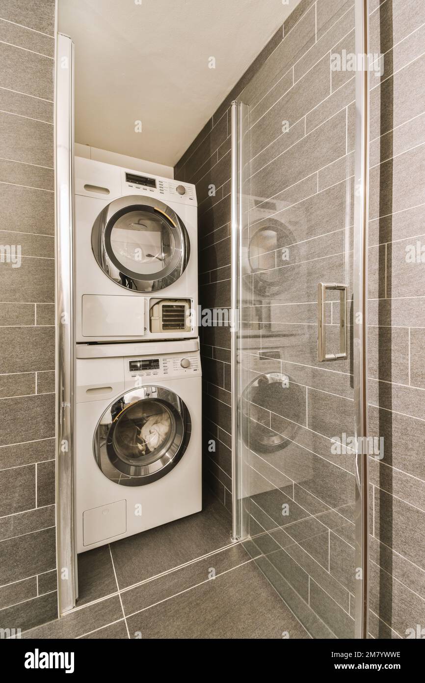 una lavanderia con lavatrice e asciugatrice accanto al box doccia di fronte  alla lavatrice Foto stock - Alamy