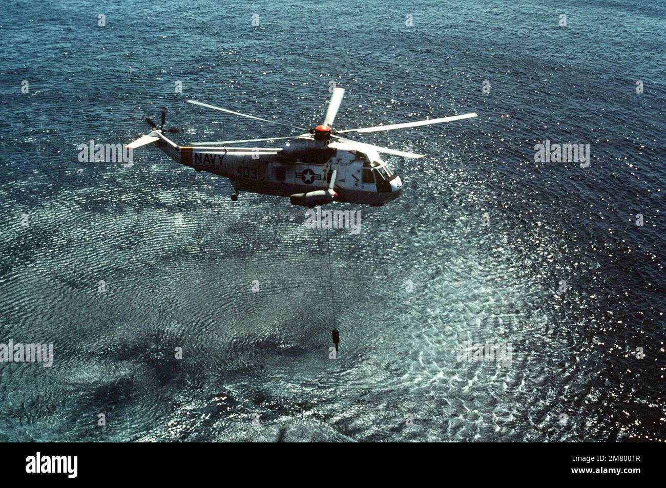 Vista lato destro aria-aria di un elicottero Navy SH-3D Sea King assegnato all'elicottero anti-sottomarino Squadron 84 durante le operazioni di volo. L'elicottero traina il sonar da immersione AQS-13. Paese: Oceano Pacifico (POC) Foto Stock