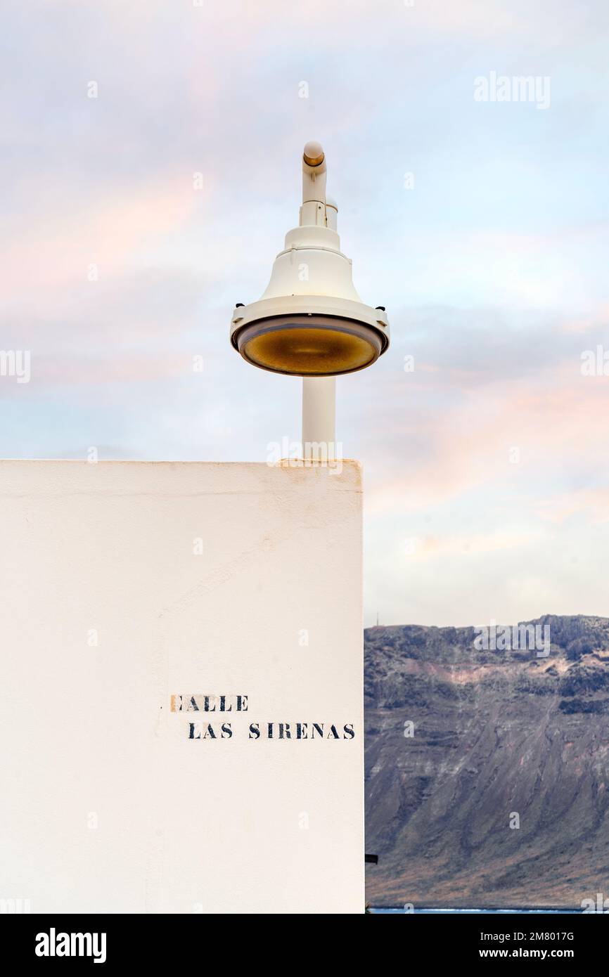 Lampada da strada bianca all'angolo della casa bianca con sfondo vulcanico dell'isola di Lanzarote, la Graciosa, Isole Canarie, Spagna Foto Stock