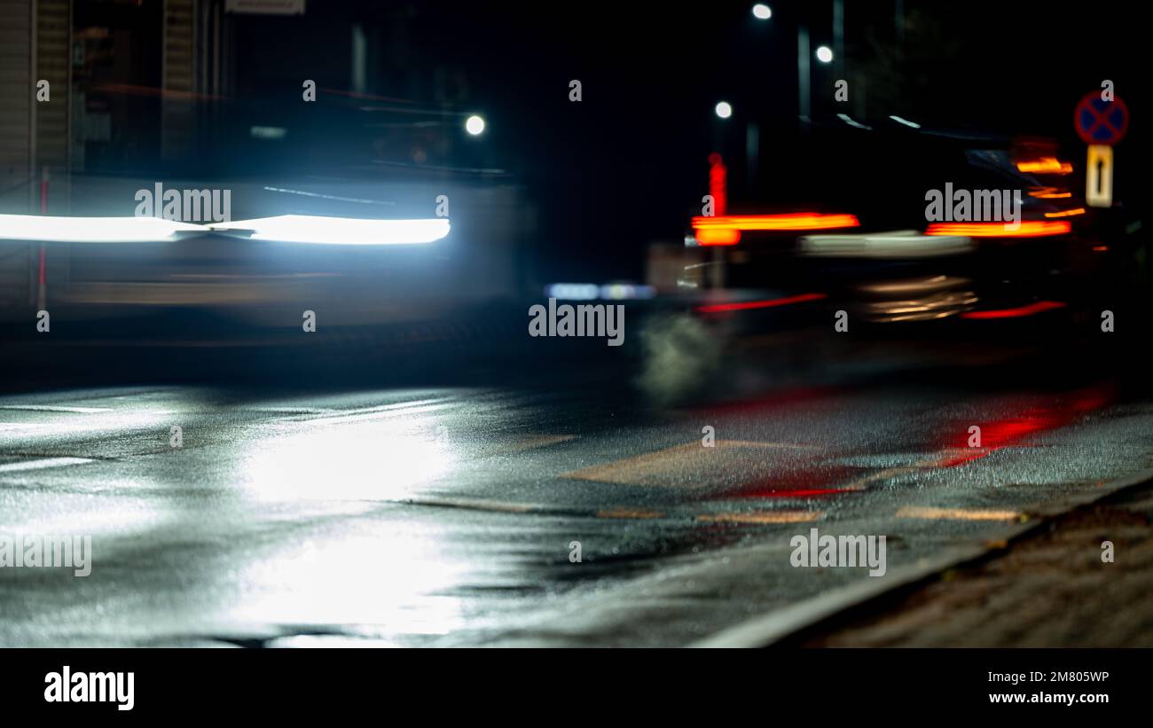 Città strada notte sfondo sfocato. Auto che si avvicinano a un passaggio pedonale. Bokeh vita notturna della città. La città di Ustzyki Dolne, Polonia. Foto Stock