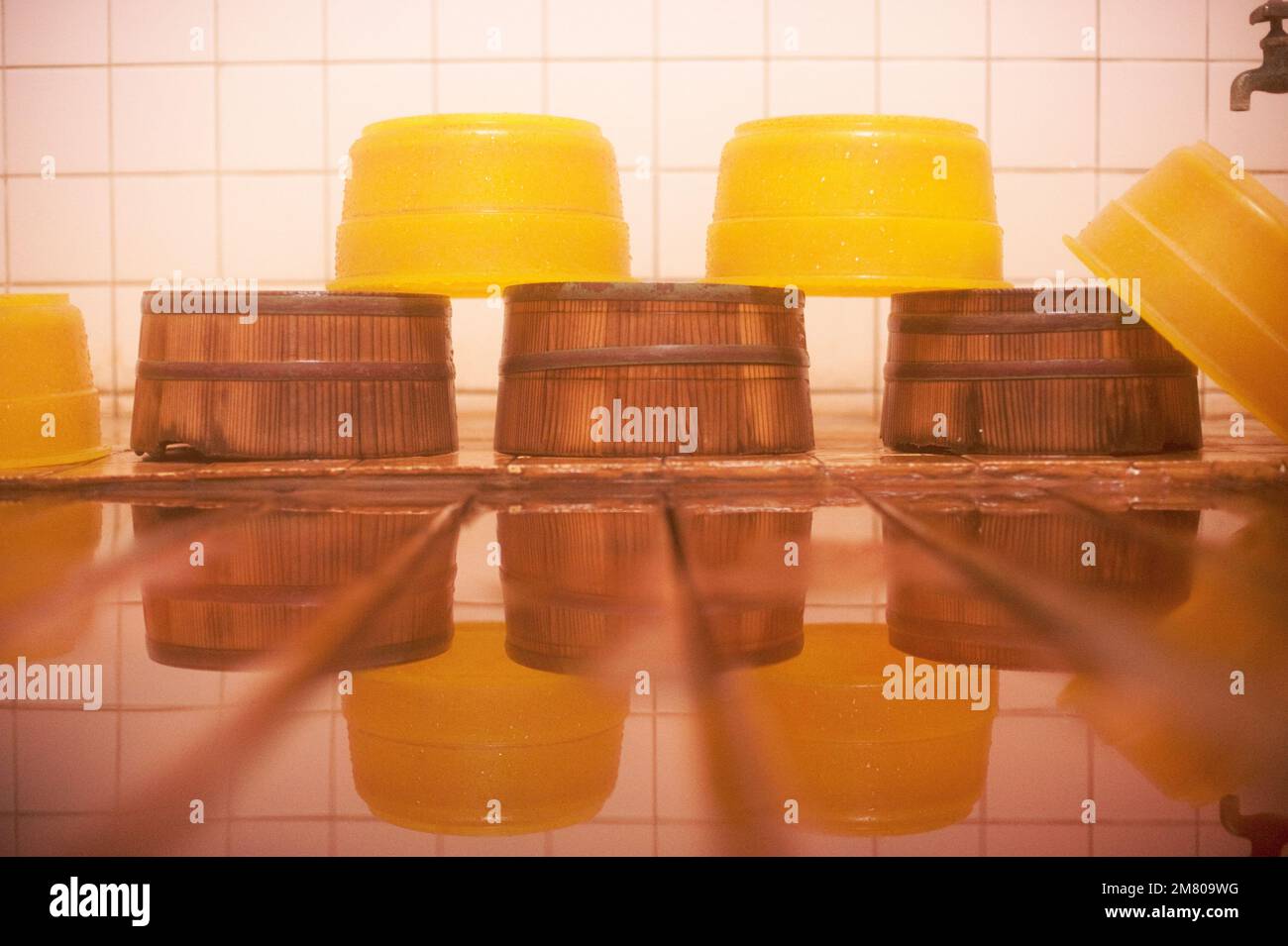 Bacini in legno e plastica sono impilati da un rubinetto d'acqua per bagnanti in un bagno termale caldo a Shibu Onsen, Nagano, Giappone. Foto Stock