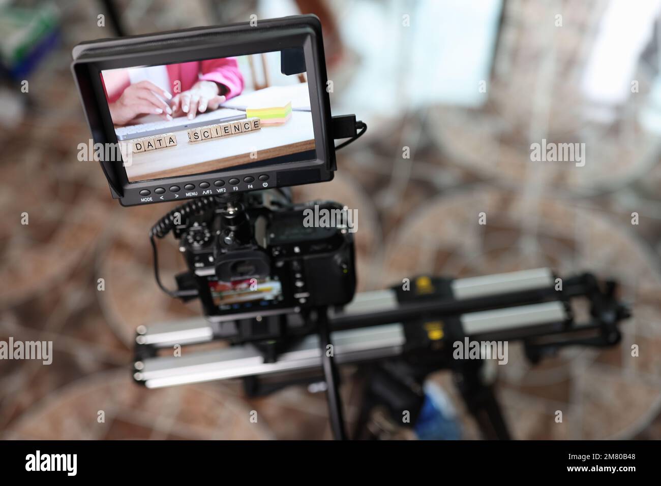 Fotocamera digitale con monitor esterno sul cursore della fotocamera per riprendere la donna che digita sulla tastiera. Foto Stock