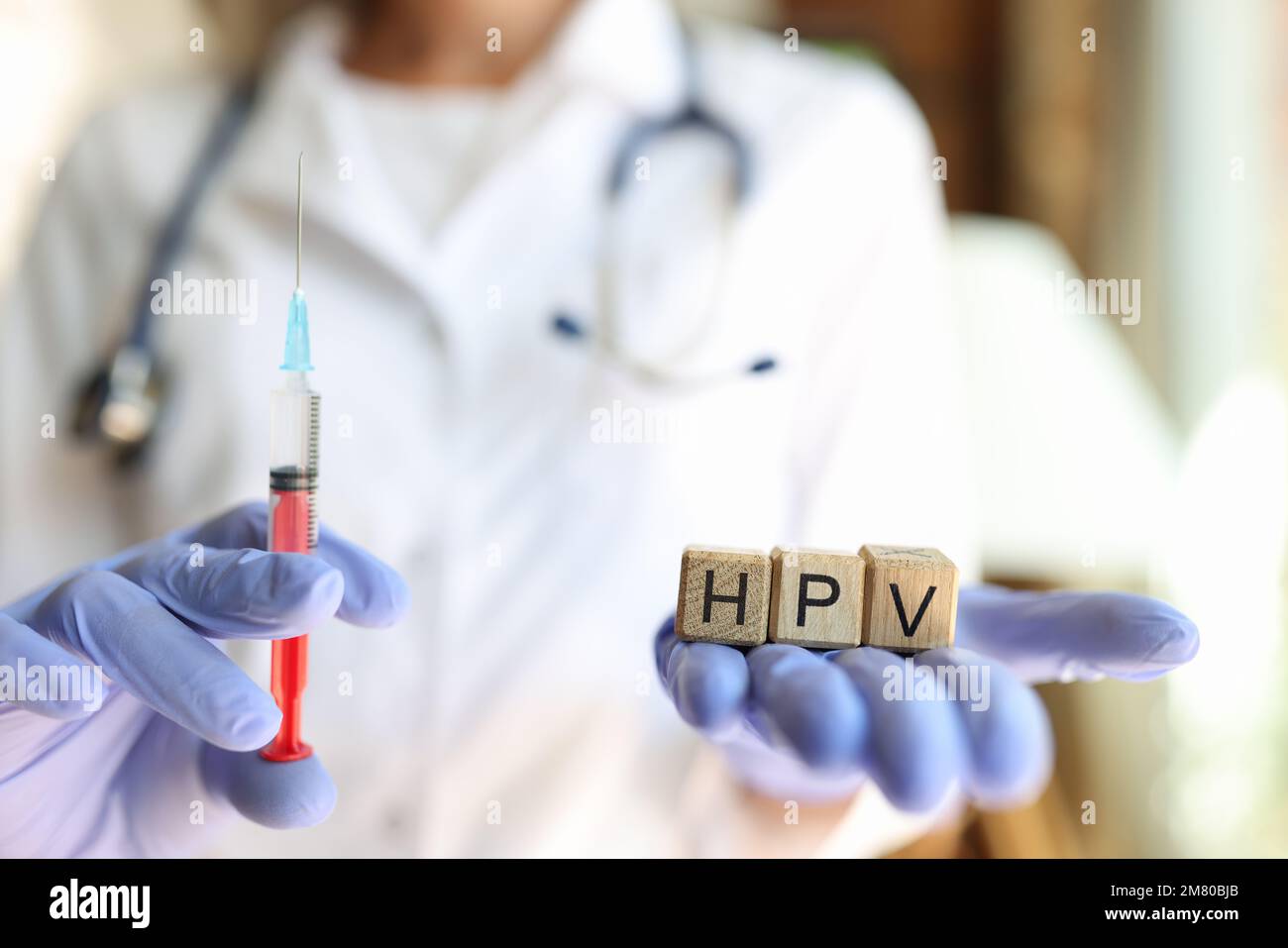 Infermiera o medico femminile con siringa e lettere HPV in mani con guanti. Foto Stock