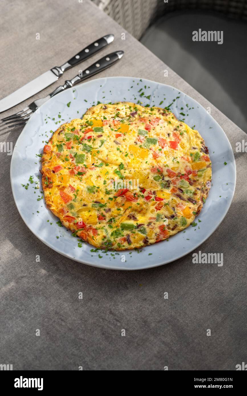 Riempite la frittata con pomodori, peperone rosso e broccoli luce sul tavolo di legno. Alimentazione sana alimenti per la colazione. Gustoso cibo di mattina. Foto Stock