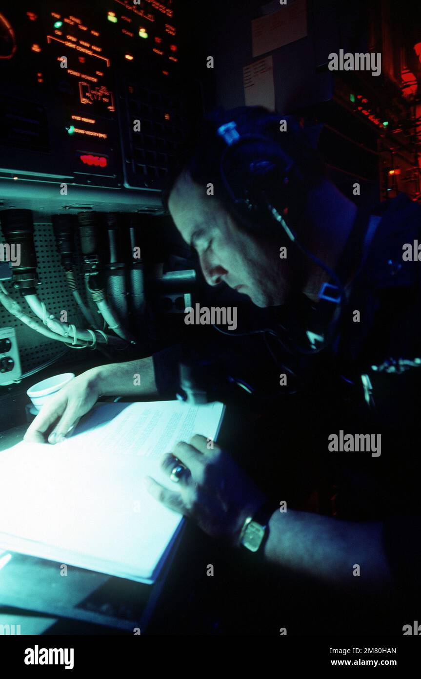Dopo aver ascoltato il battito dell'elica di un contatto sonar, un tecnico sonar a bordo del sottomarino di attacco nucleare della classe Los Angeles USS LA JOLLA (SSN-701) va al manuale per identificare la classe di nave che emette il suono. Paese: Oceano Pacifico (POC) Foto Stock