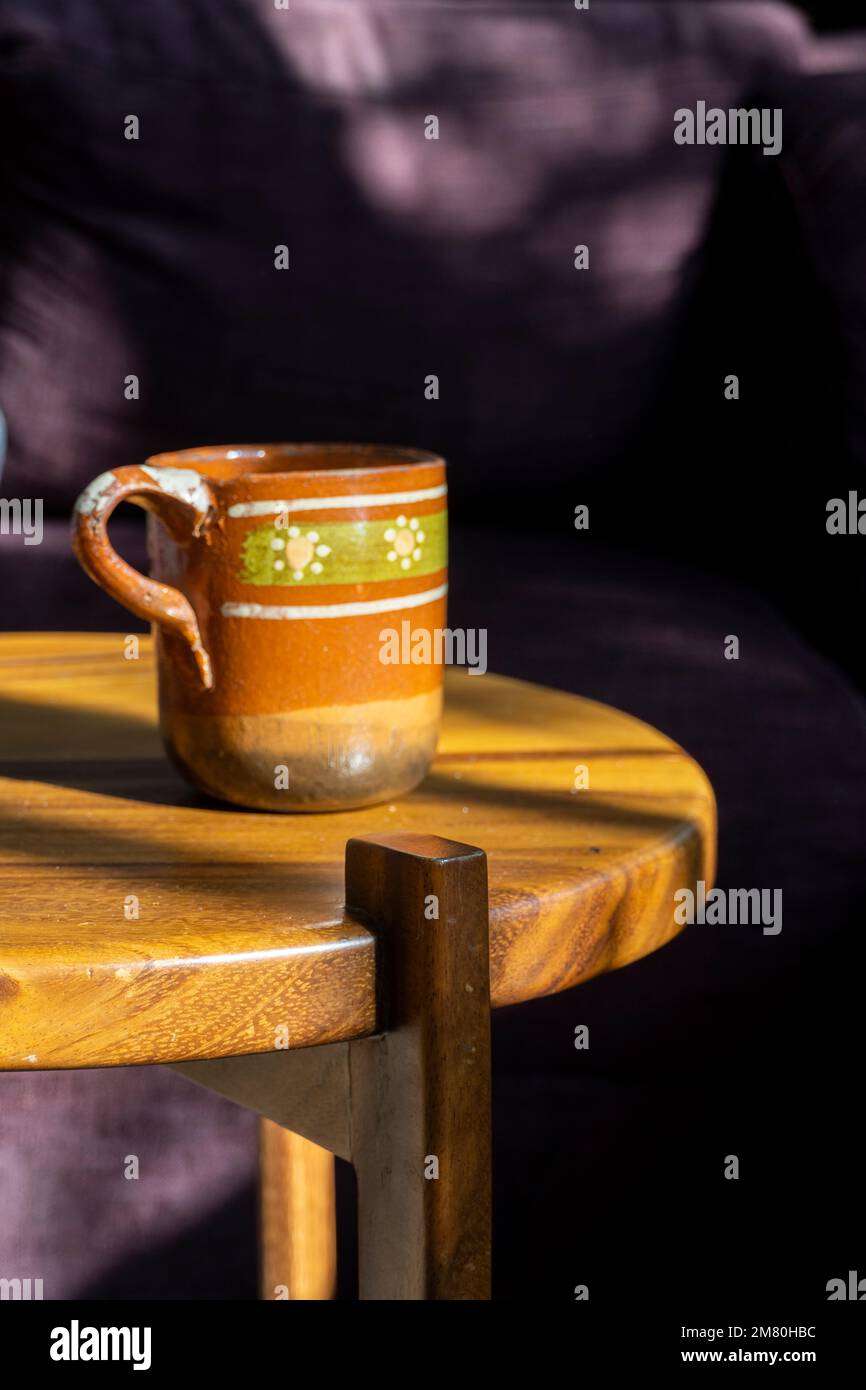 luz sol tazza di argilla, argilla naturale con pigmento, piccola tazza da caffè con base bruciata su tavolo di legno Foto Stock