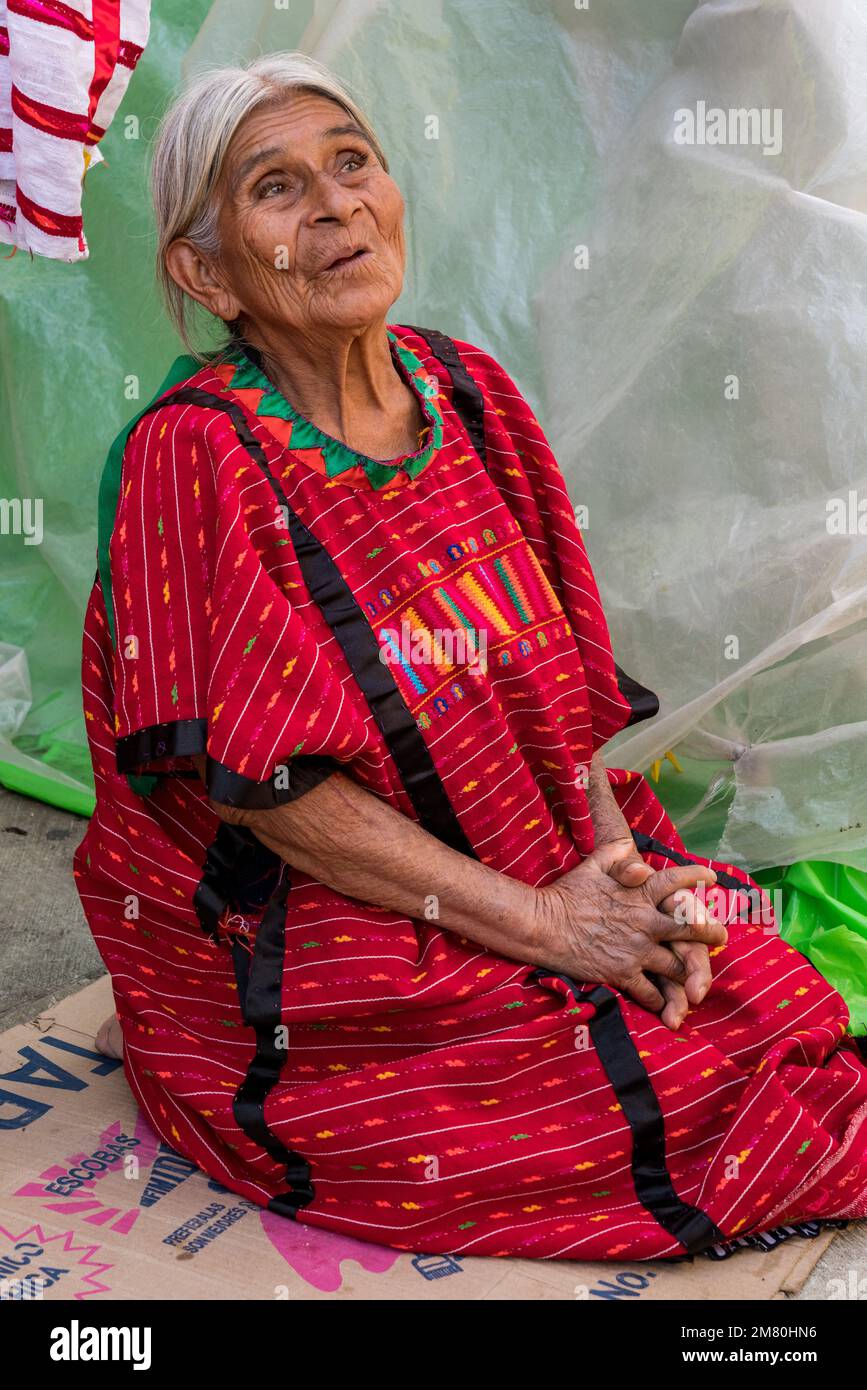 Un'anziana donna indigena indiana Trique nel tradizionale huipil tessuto a mano seduto sulla strada nella storica Oaxaca, Messico. Foto Stock