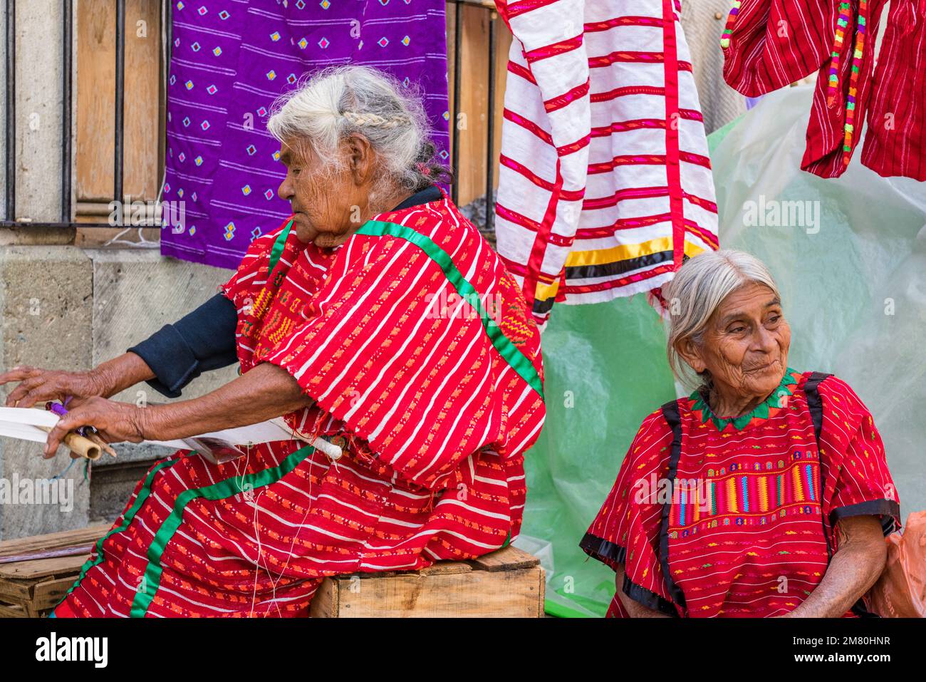 Una donna indiana indigena Trique tesse tessuto su un telaio backstrap vicino allo Zocalo nel centro storico di Oaxaca, Messico. Patrimonio mondiale dell'UNESCO Foto Stock