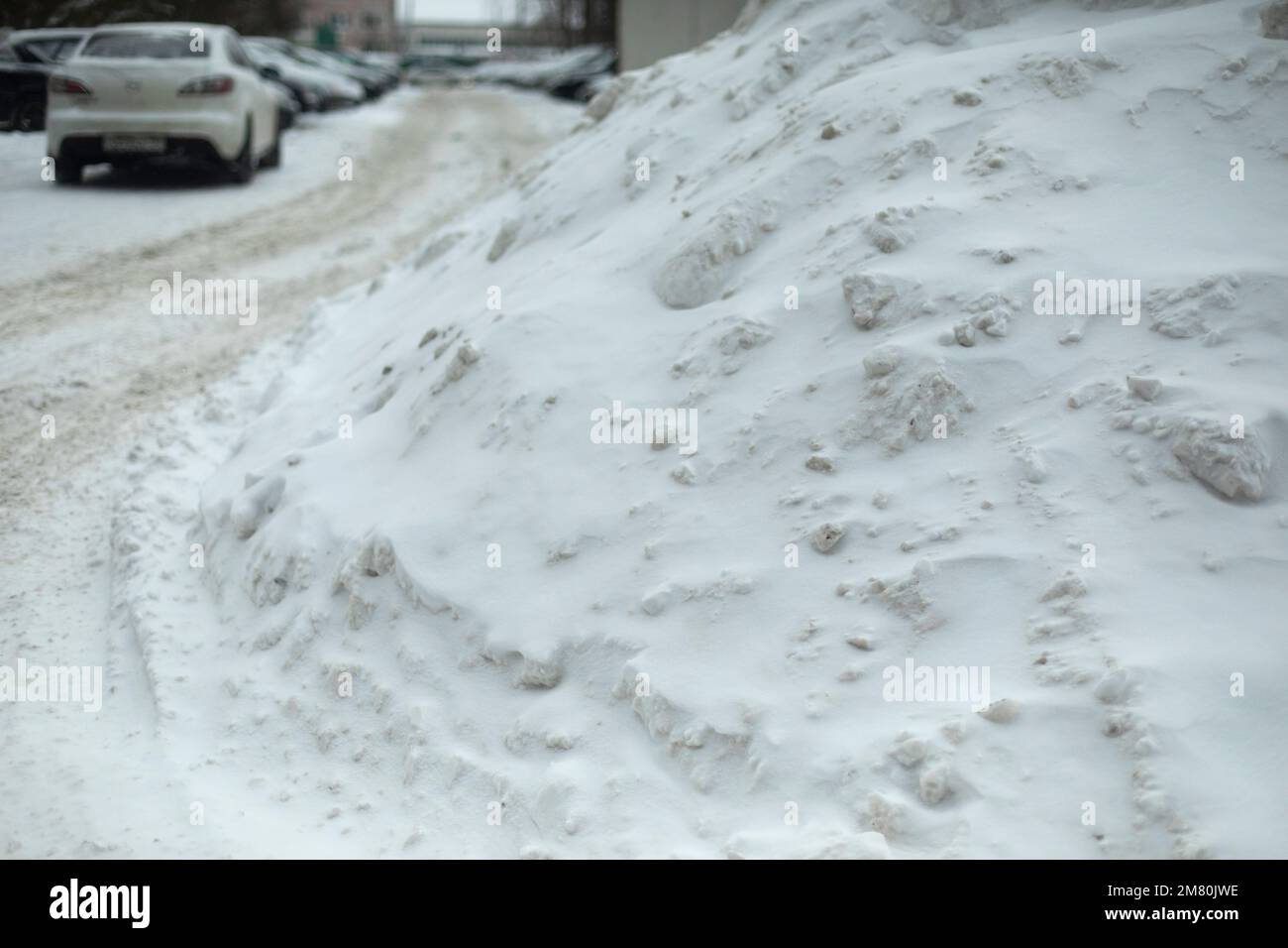 Neve nel parcheggio. Nevicate su strada. Dopo la tempesta di neve. Vetrino di ghiaccio. Foto Stock