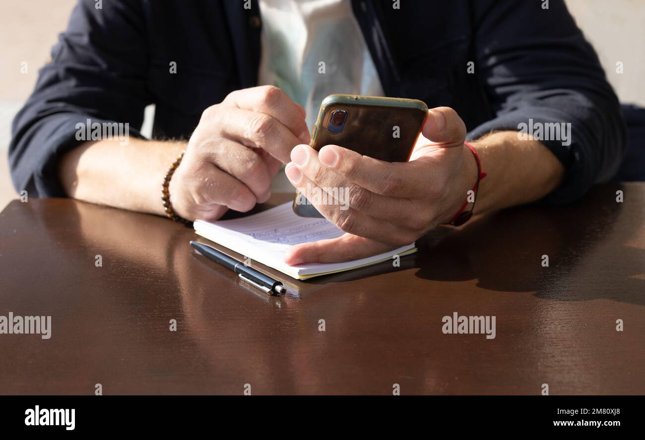 un uomo sconosciuto tiene un telefono in una mano, tocca lo schermo con un dito Foto Stock