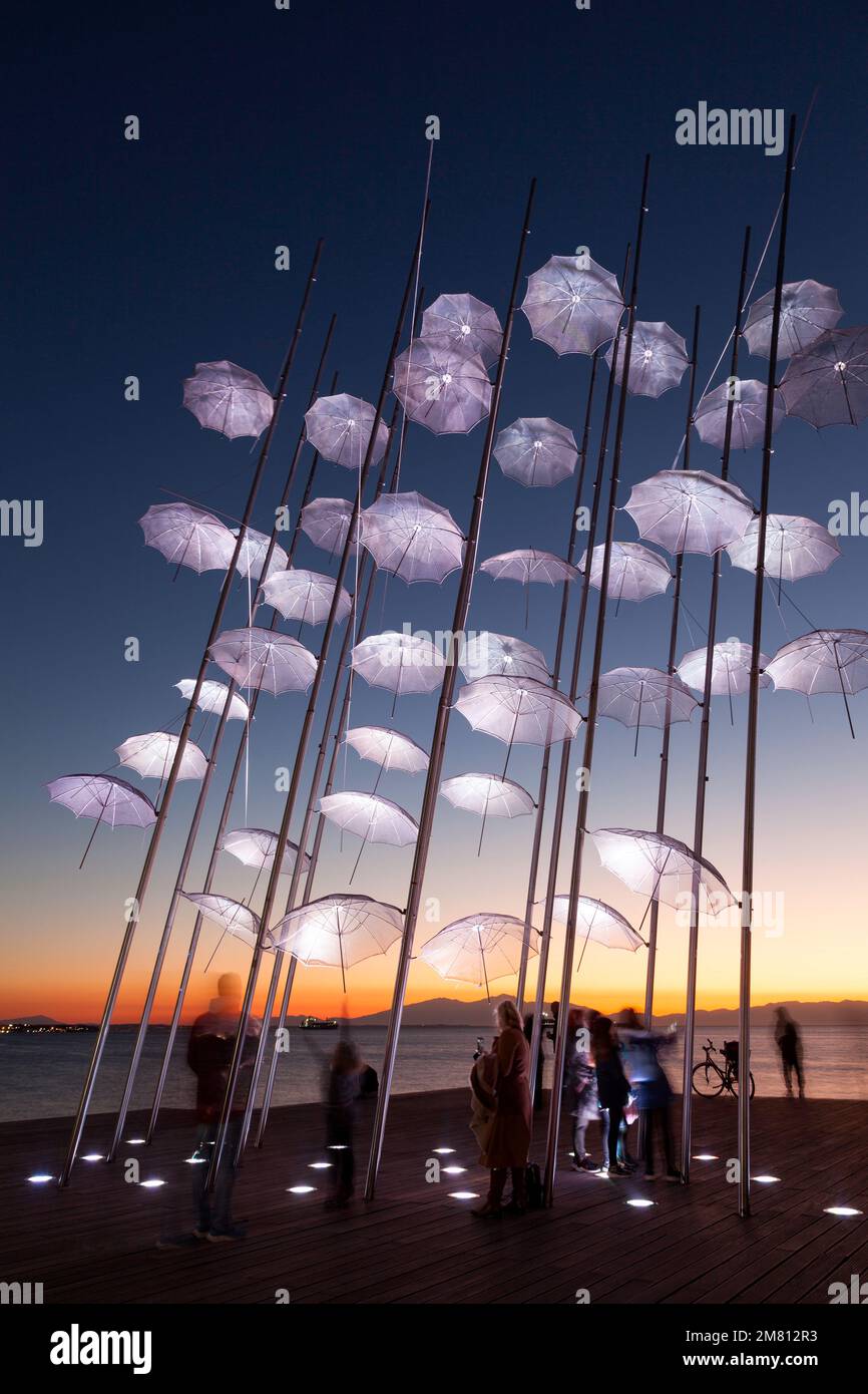 Le persone che si godono l'ora del tramonto presso i famosi ombrelli di Zongolopoulos, nel quartiere Nea Paralia (lungomare) di Salonicco. Foto Stock