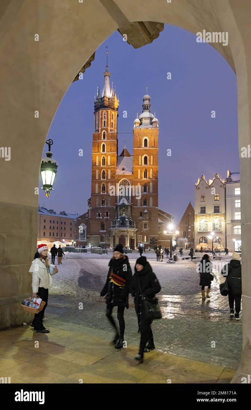 La chiesa di San Marys di Cracovia è illuminata di notte; vista attraverso un arco della Sala dei tessuti in inverno, la piazza principale del mercato di Cracovia, la città vecchia di Cracovia, la Polonia di Cracovia Foto Stock