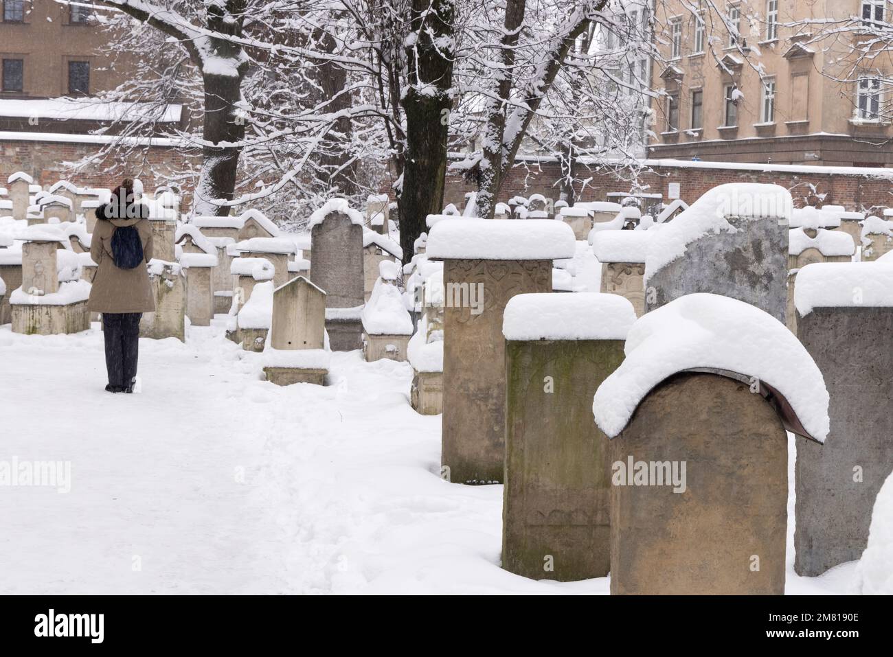 Quartiere ebraico di Cracovia - un visitatore nel cimitero della Sinagoga di Remuh nella neve d'inverno, Cracovia, Polonia Europa Foto Stock