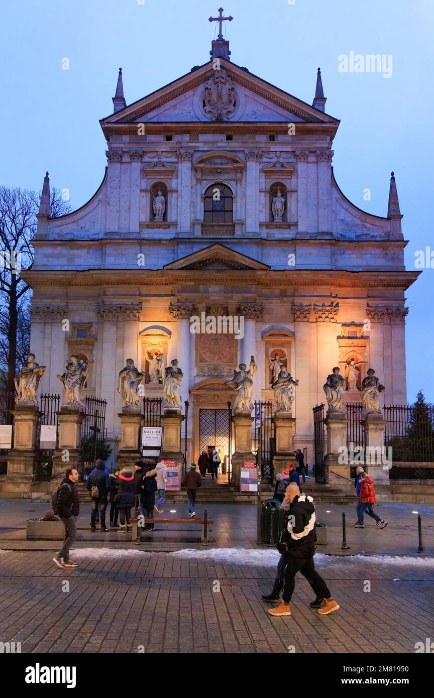Scena della Via di Cracovia - persone che camminano davanti alla Chiesa dei Santi Pietro e Paolo in una serata invernale, Cracovia Città Vecchia, Cracovia Polonia Europa Foto Stock