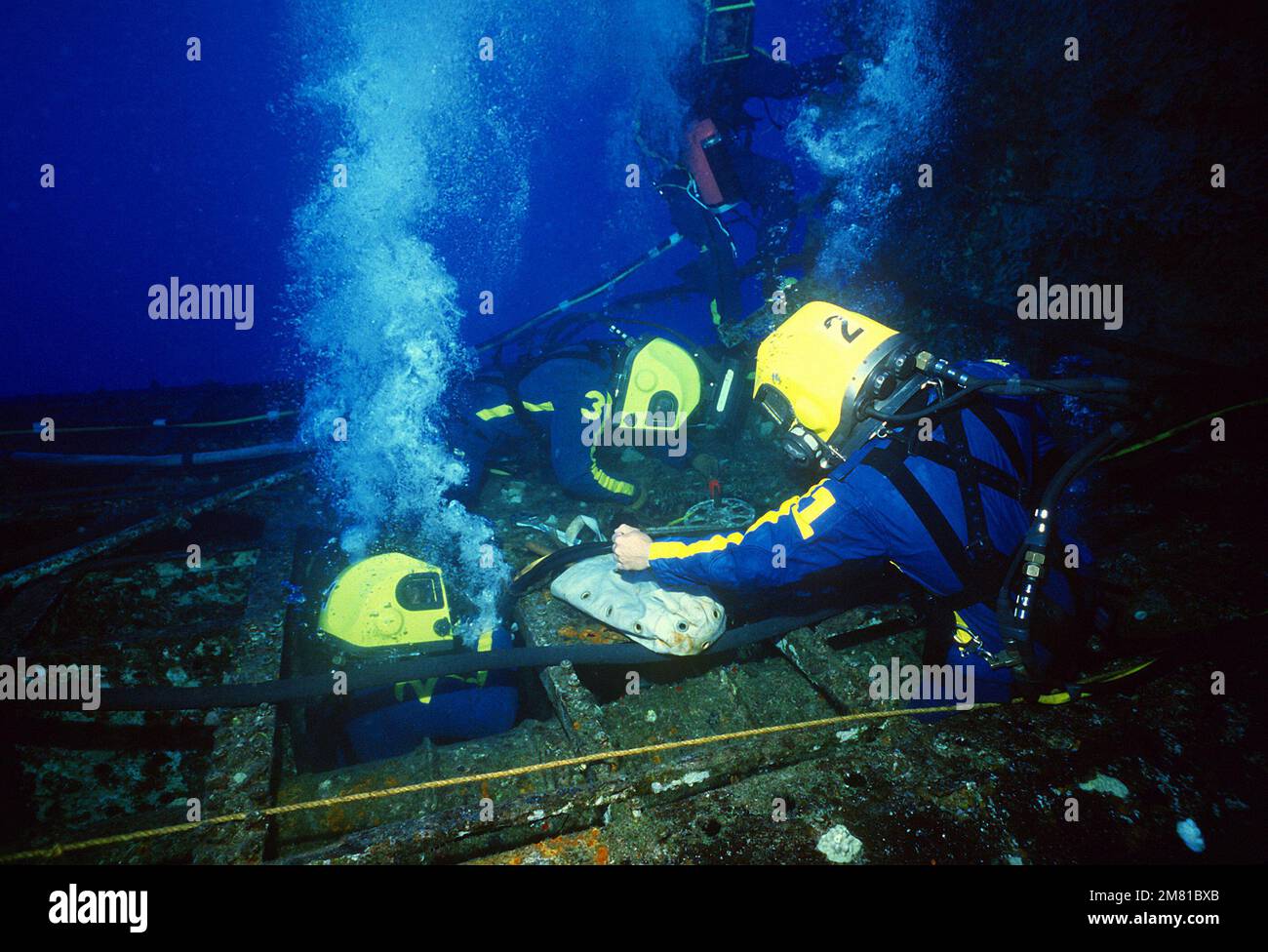 Quattro subacquei della Marina a elica con tubi d'aria in superficie lavorano per sollevare lo scafo del sottomarino ex-USS BLUEGILL (SS-242) durante l'esercizio di salvataggio 83 del sottomarino del Pacifico (PACSUBSALVEX-83) al largo della costa di Maui. Oggetto operazione/Serie: PACIFIC SUBMARINE SAVAGE EXERCISE 83(PACSUBSALVEX-83) Stato: Hawaii (HI) Paese: Stati Uniti d'America (USA) Foto Stock