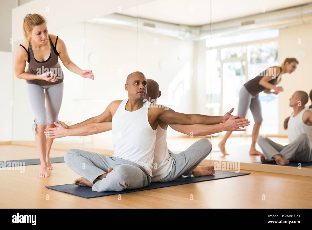 Persone che praticano yoga con partner in studio Foto Stock