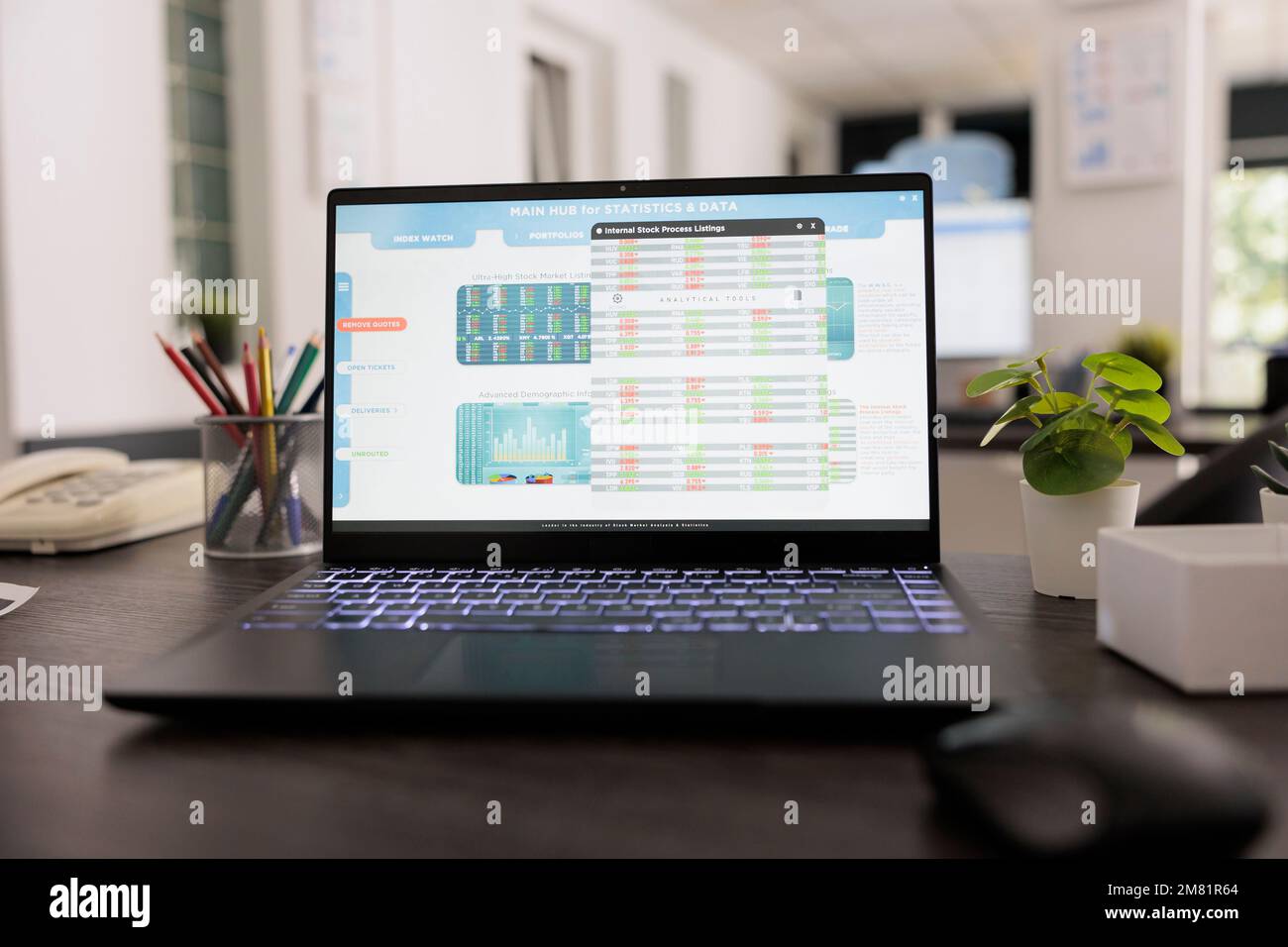 Vista ravvicinata del display del notebook con software di dati finanziari leader in una società di trading di investimenti. Postazione di lavoro vuota al mattino con impianto e attrezzature di lavoro sulla scrivania. Foto Stock
