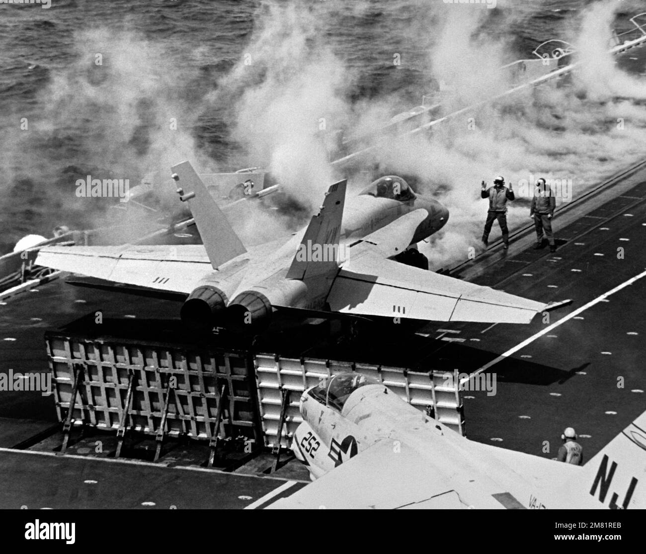 Vista posteriore destra di un aeromobile F/A-18 Hornet assegnato a Marine Fighter Attack Squadron 314 (VMFA-314) in preparazione al decollo dalla COSTELLAZIONE USS della portaerei (CV-64) durante una valutazione operativa (OPEVAL). In primo piano è un aereo Corsair II a-7 di Light Attack Squadron 122 (VA-122). Paese: Oceano Pacifico (POC) Foto Stock