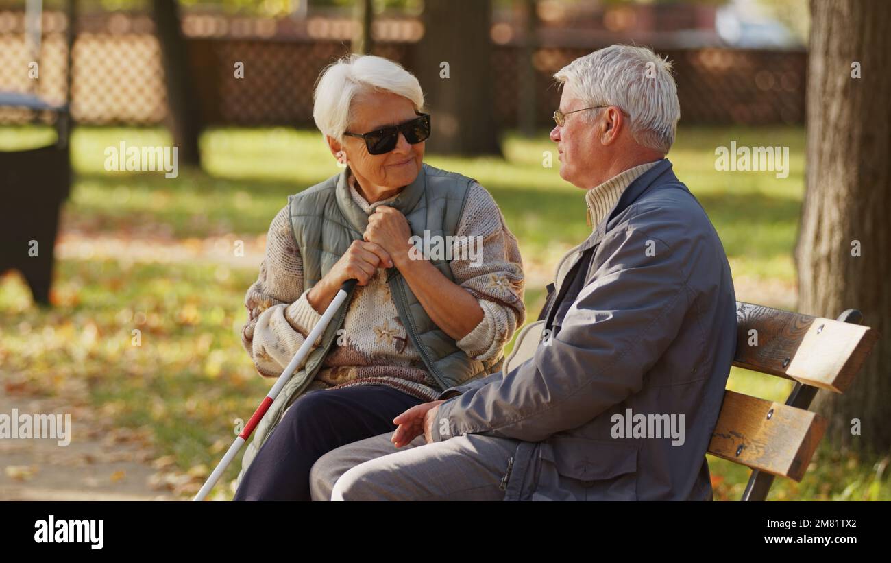 Donna anziana cieca con il marito seduto su una panchina nel parco. Foto di alta qualità Foto Stock